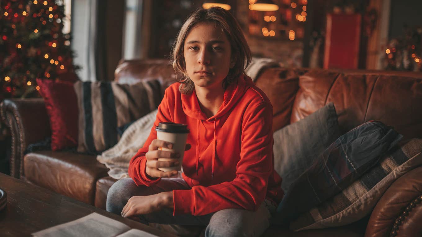 young adult with long hair thoughtful look sad eyes negative mood at home during the holidays