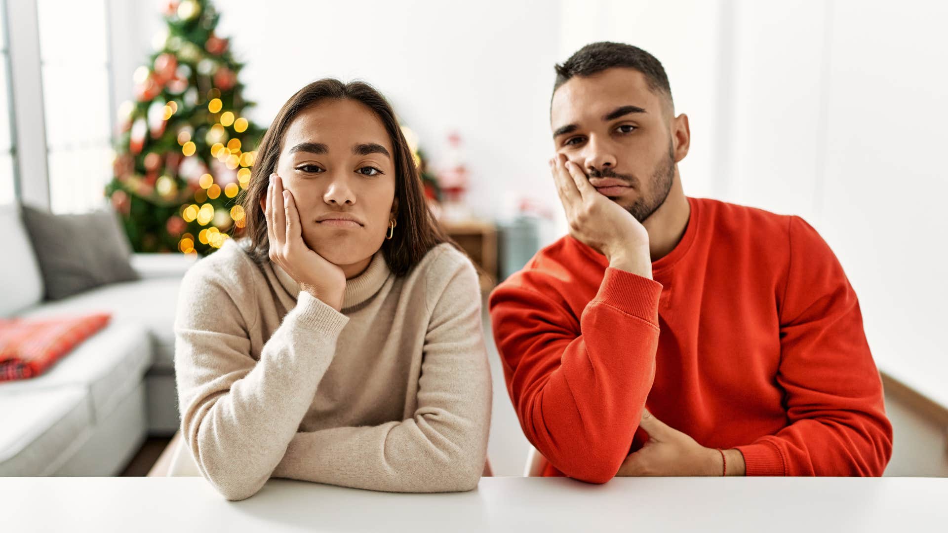 Two adult siblings looking annoyed at the table.