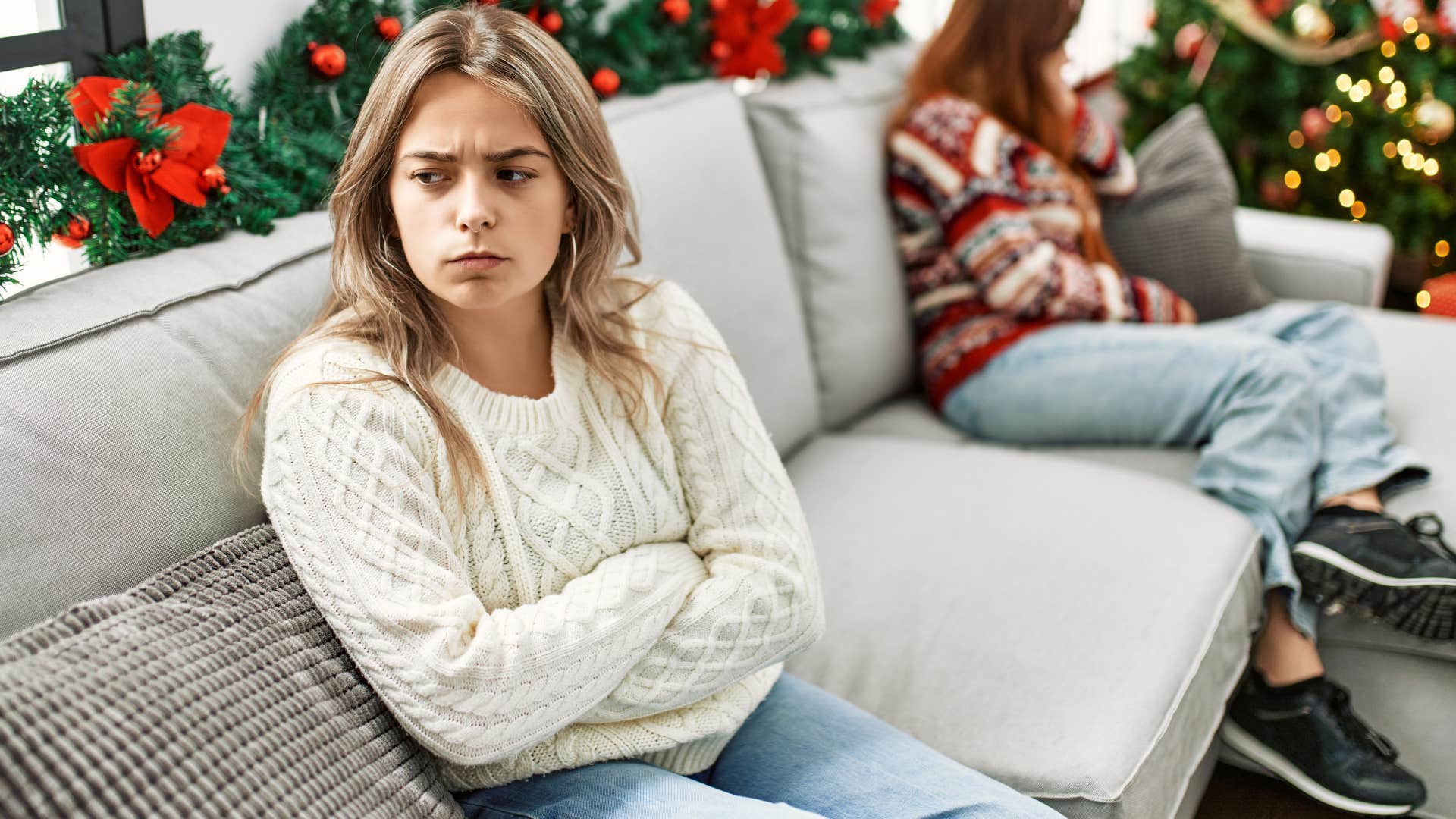 Young woman looking upset turned away from her mom on the couch.