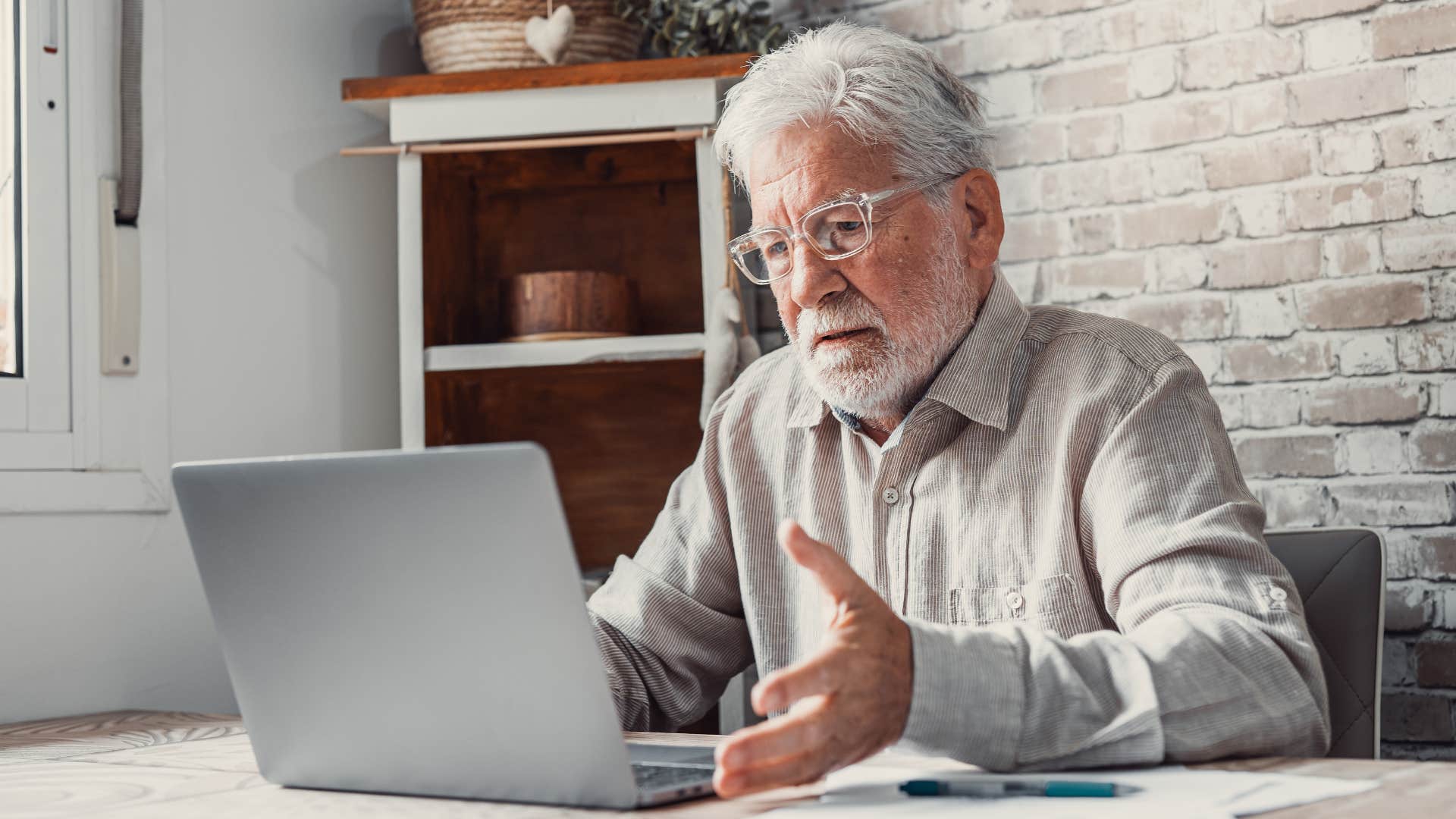 Older man looking annoyed on his laptop. 