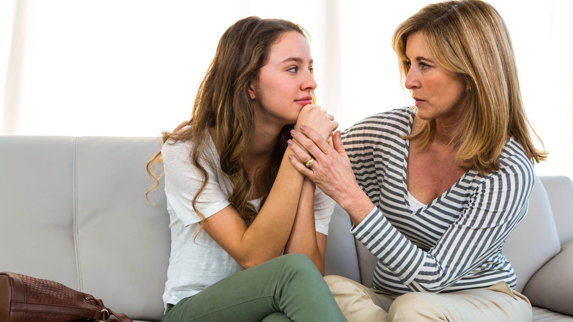 Mom comforting her daughter on the couch.