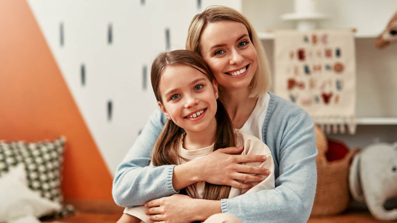 happy mother holding smiling daughter in playroom