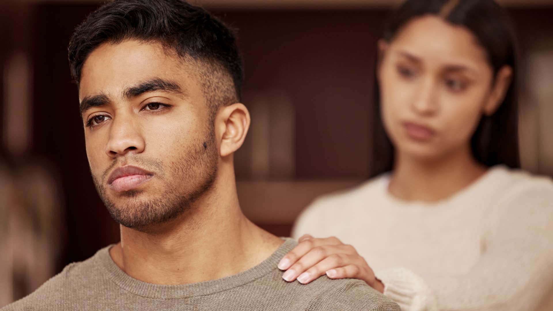 Emotional man turned away from comforting partner.