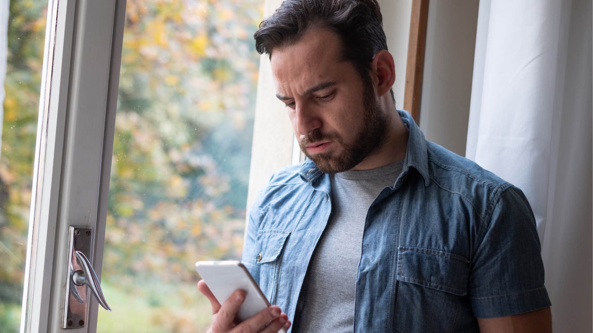 Man looking upset texting on his phone.