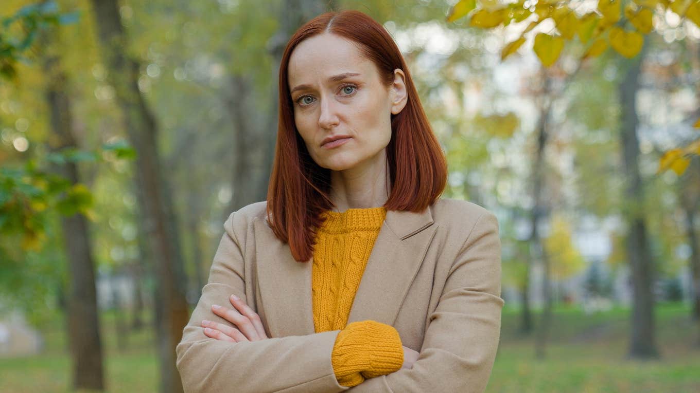 offended woman standing outside with her arms crossed