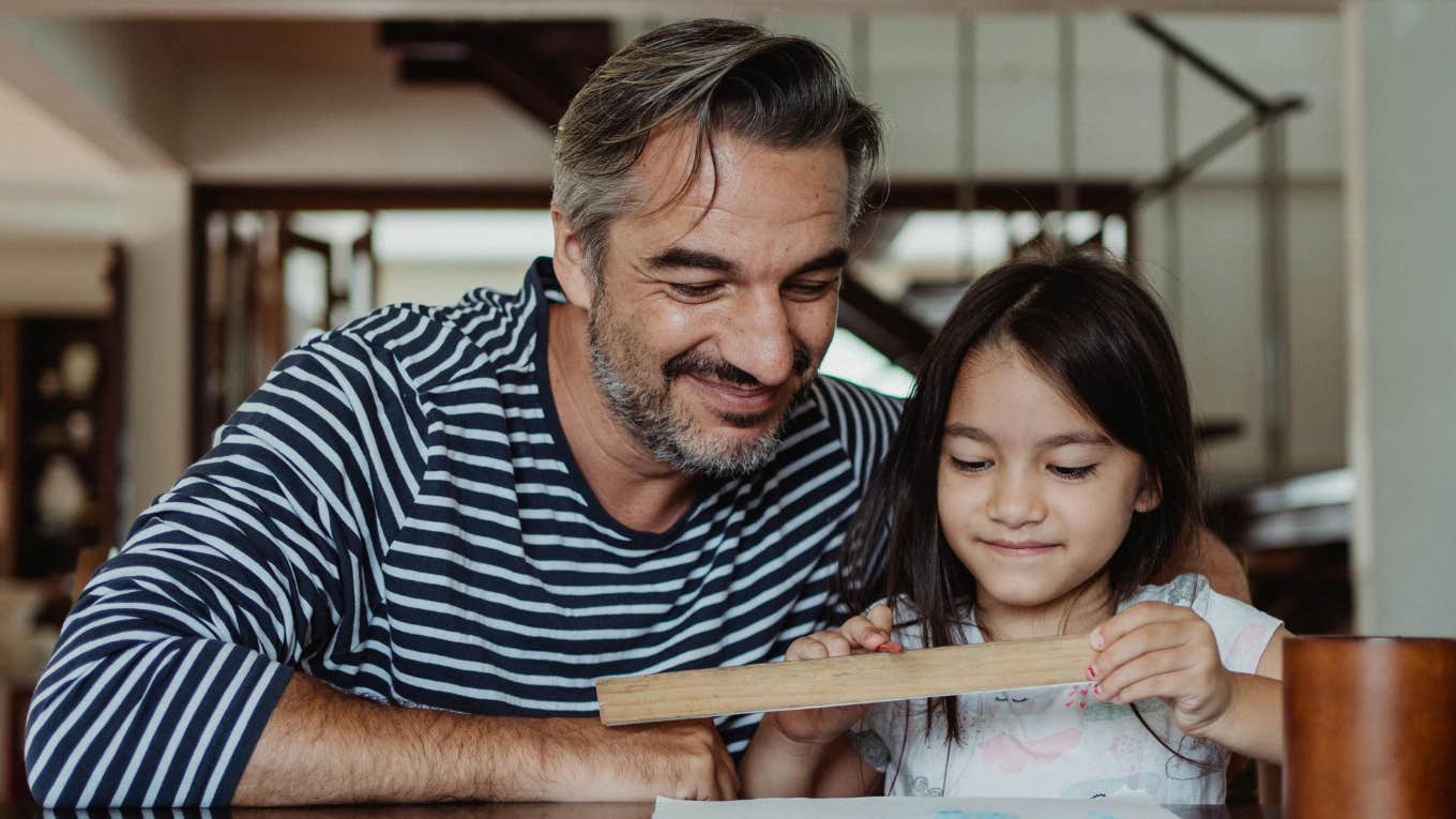 Father and daughter looking at wooden ruler