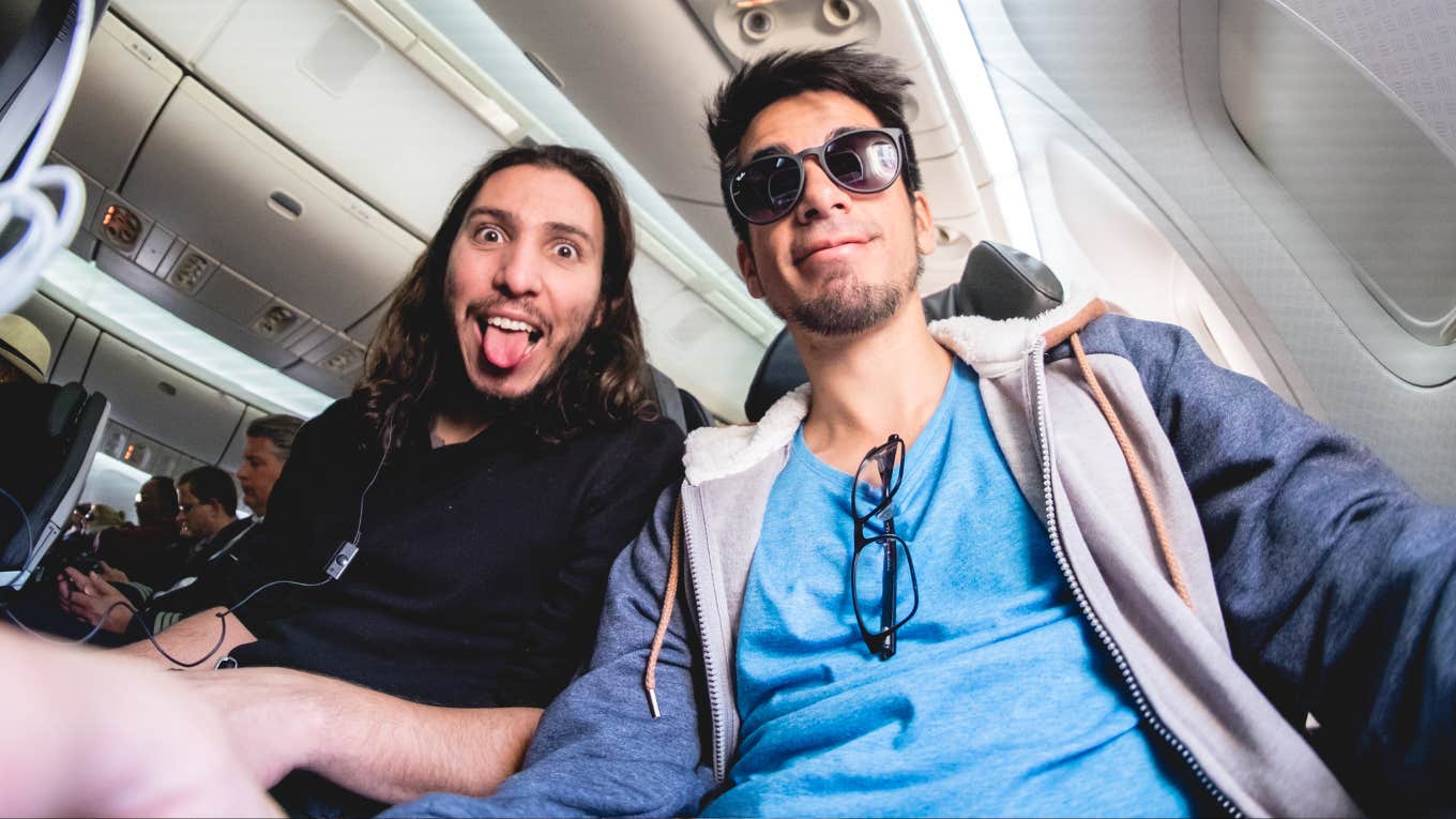 Two happy guys inside a flight on a plane