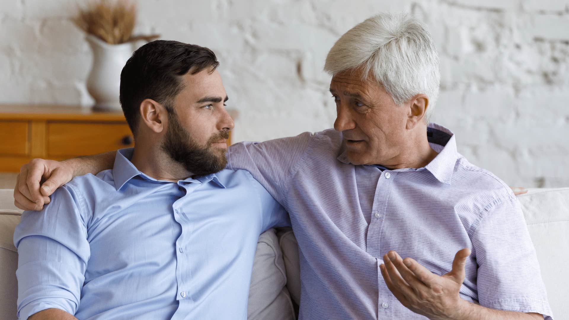 two men discussing something on the couch