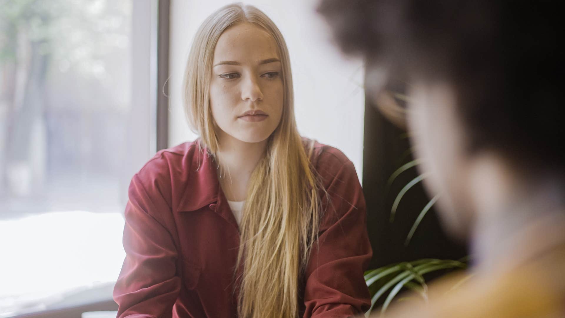 Blonde woman looking sad talking to a man.