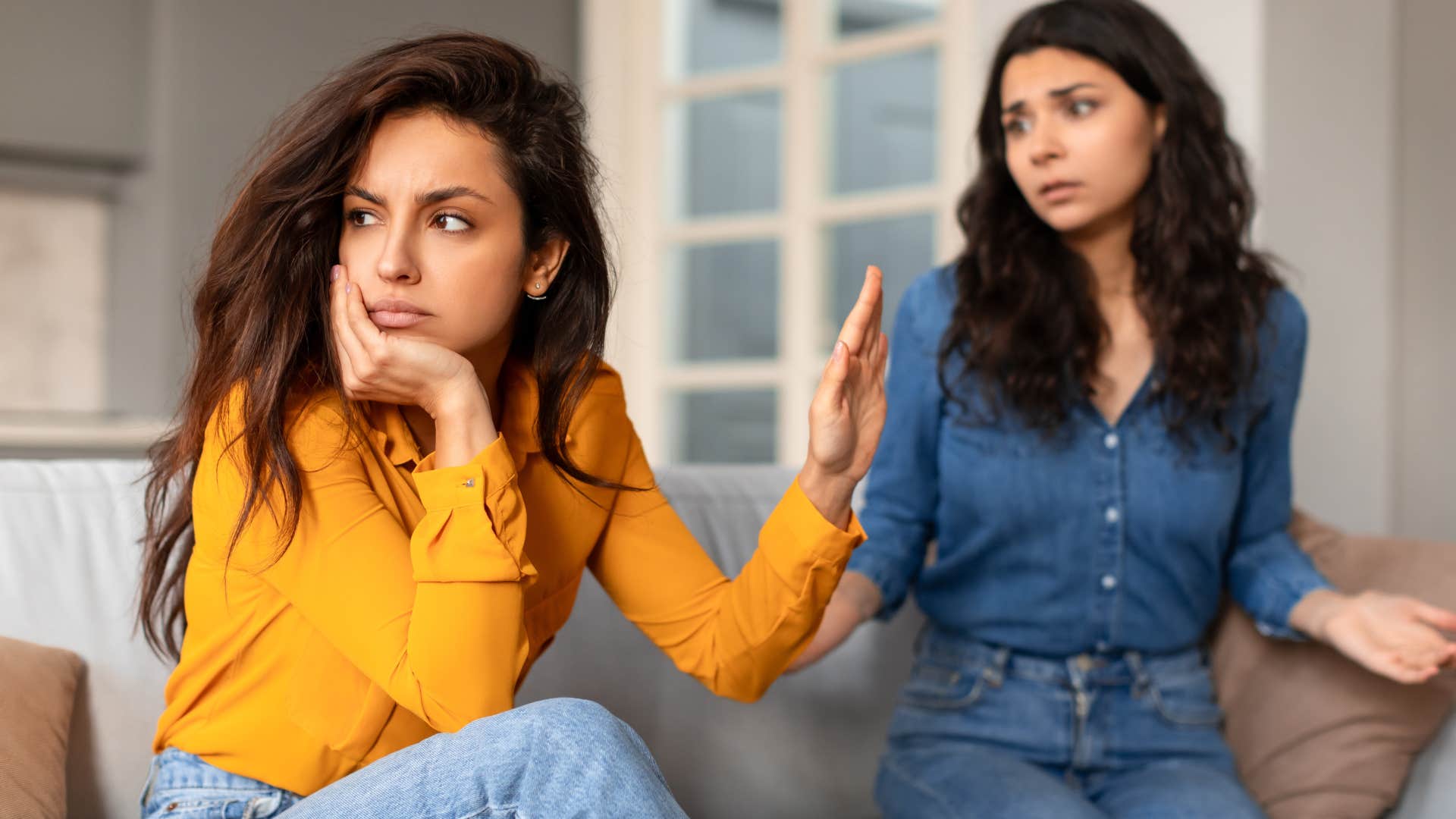 Woman turned away and holding her hand up to a friend.