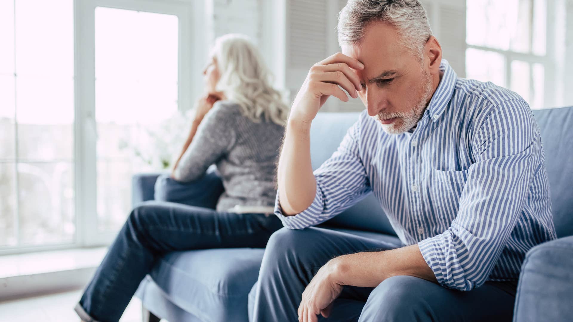 Older man with his head in his hands next to his wife