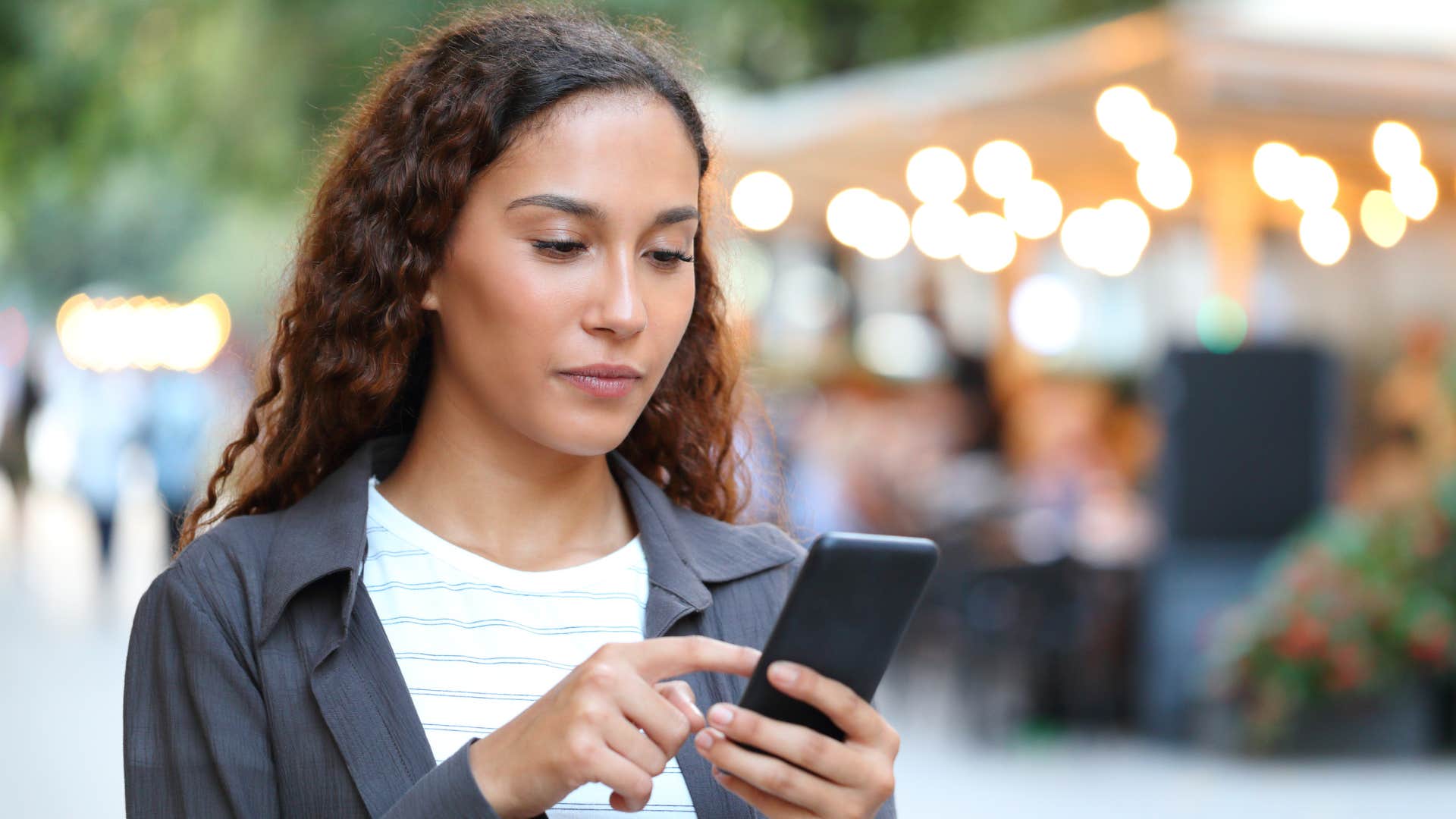 Woman looking annoyed staring at her cell phone.