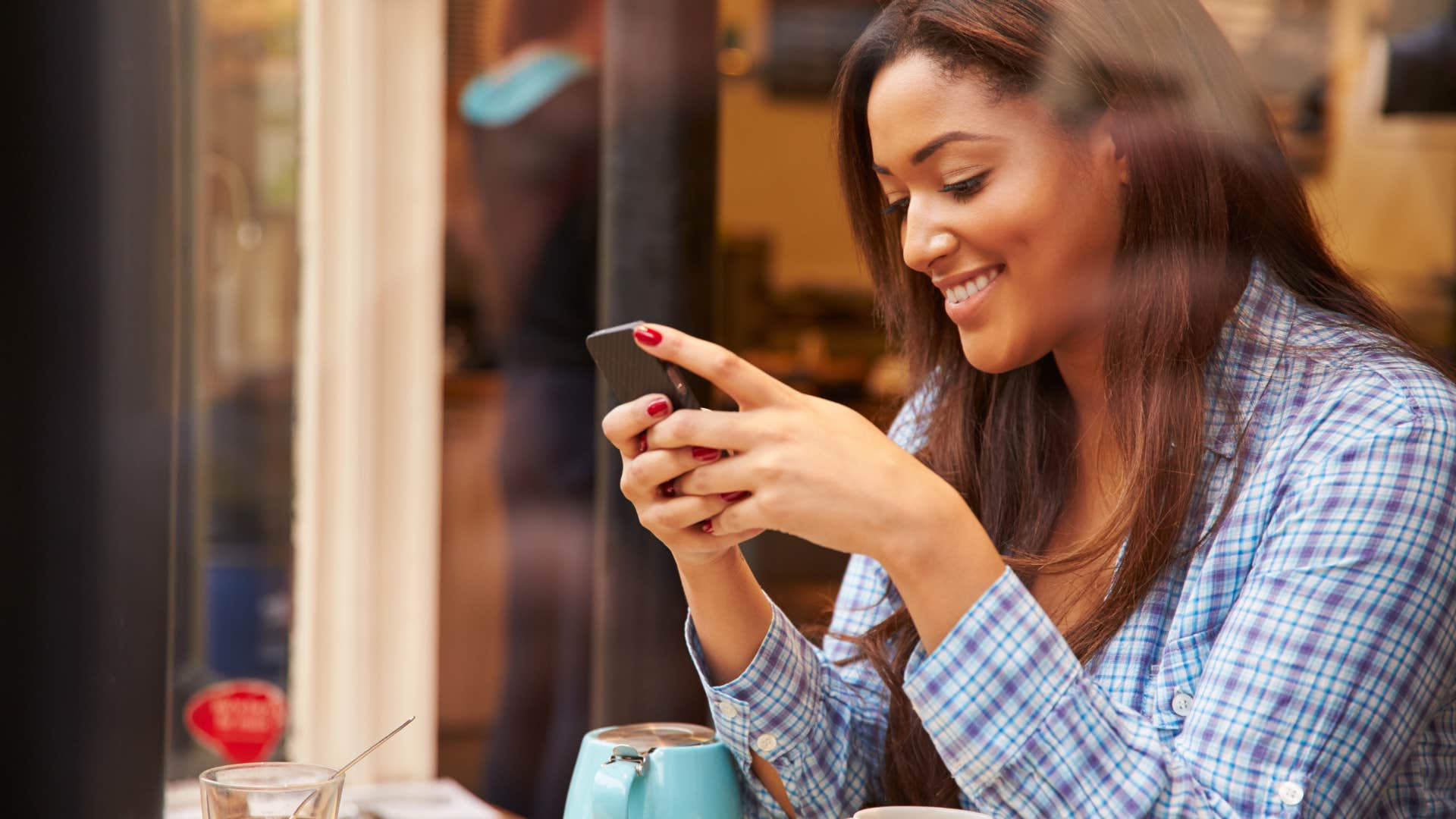 Woman smiling while texting on her phone. 