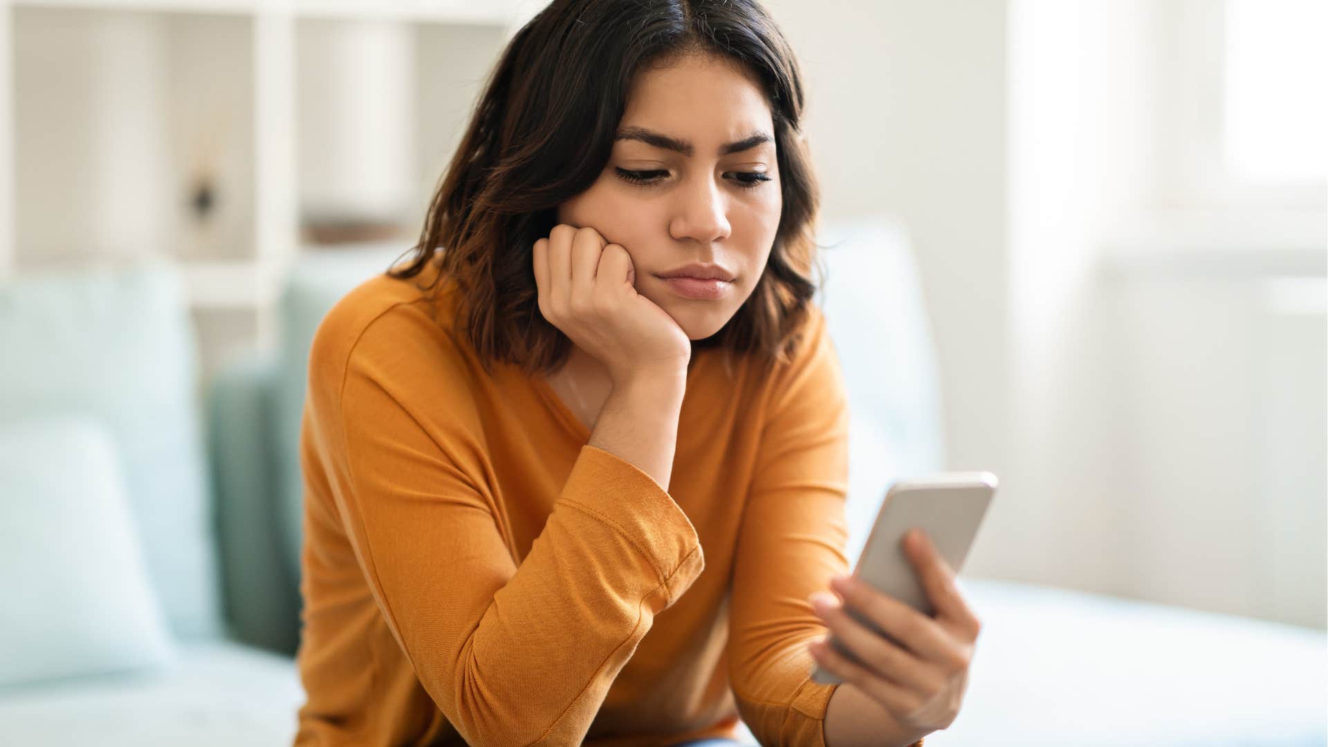 Woman looking upset staring at her phone. 