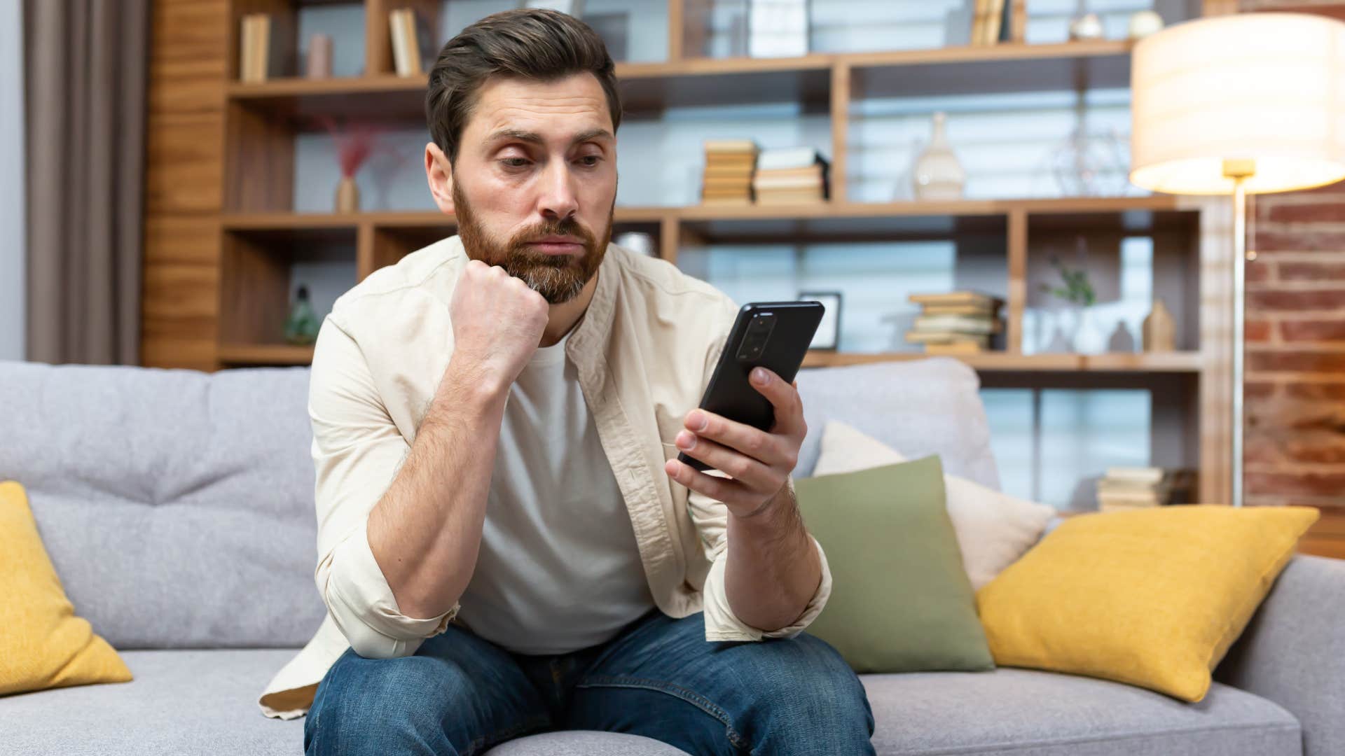 Man looking tired while staring at his cell phone.