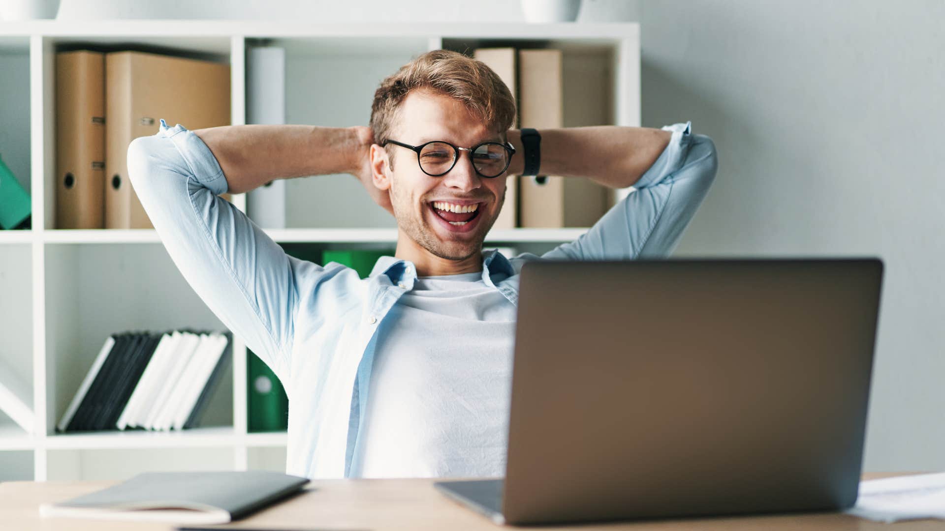 Man smiling and leaning back in his desk chair.