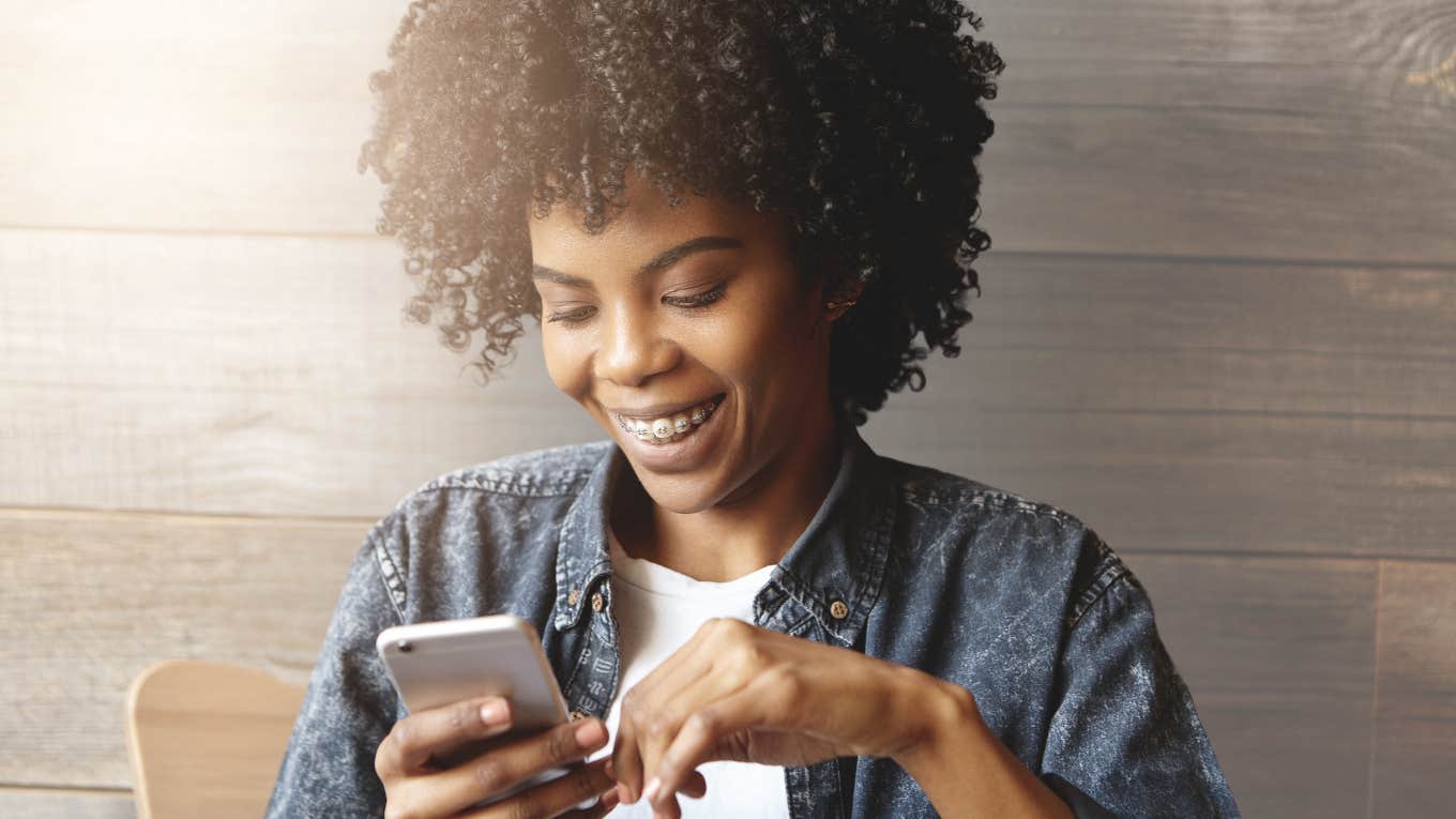 Woman smiling and looking at her cell phone.