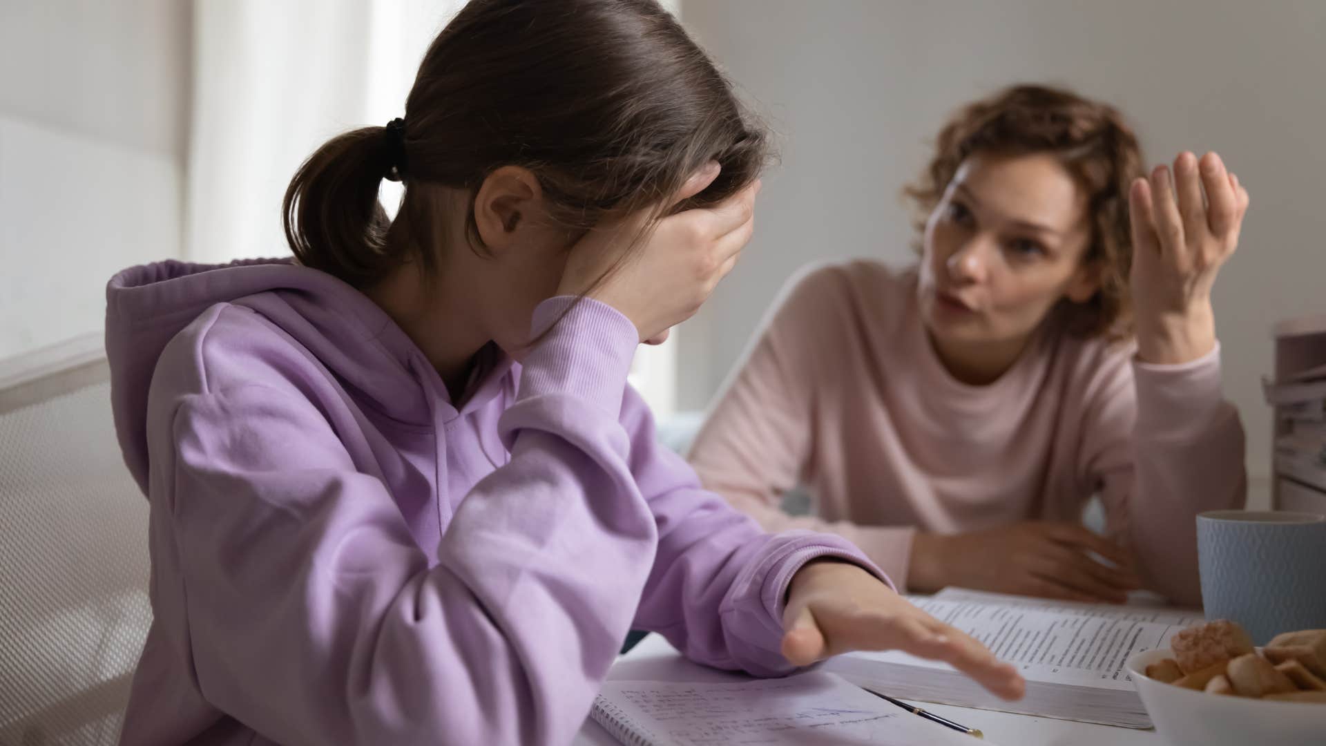 Young girl looking upset while her mom talks to her.