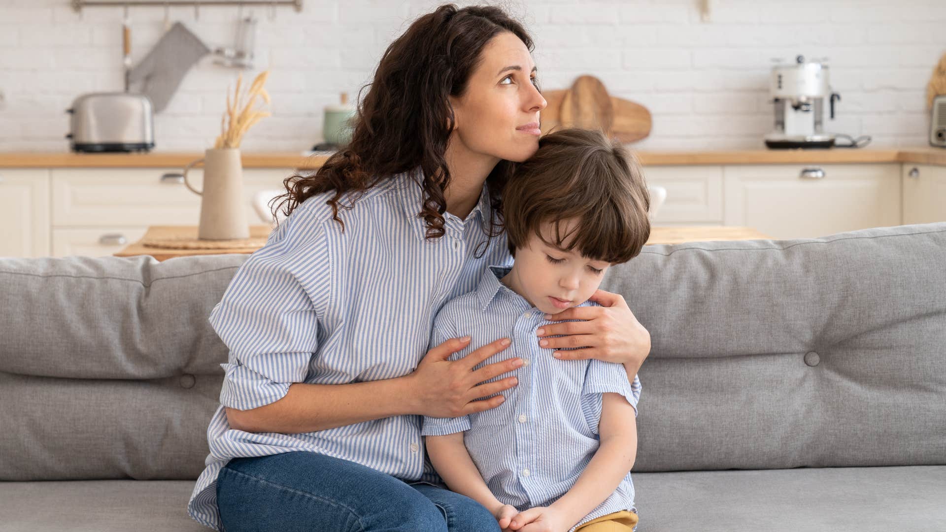 Woman hugging her upset son on the couch.