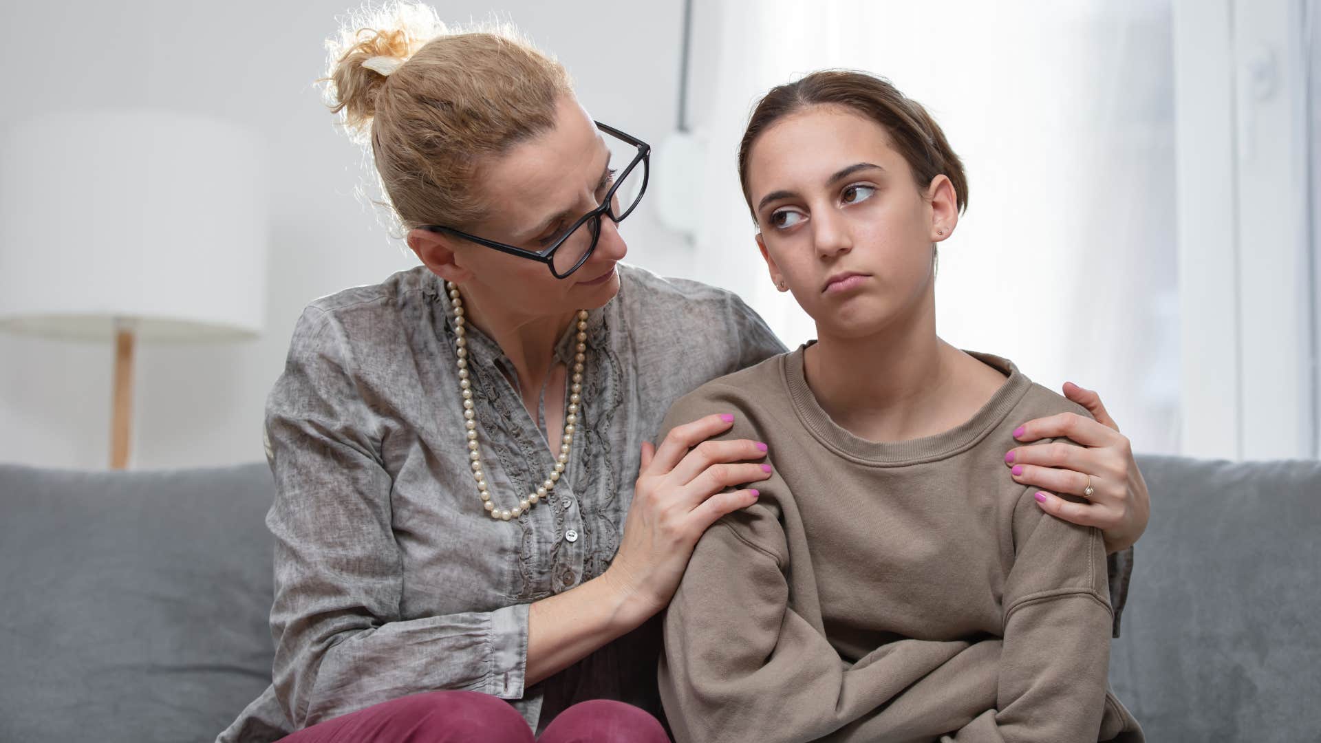 Woman holding her upset daughter's shoulders.