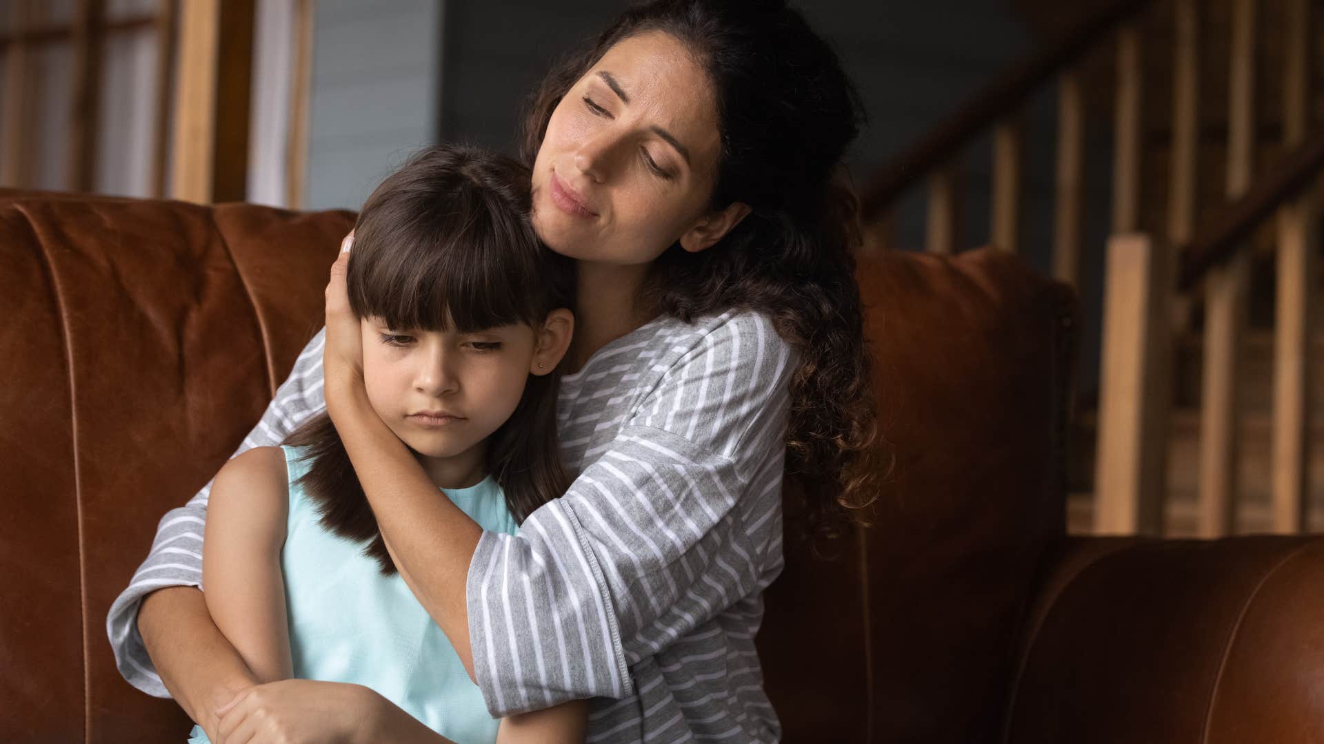 Mom hugging her upset daughter.