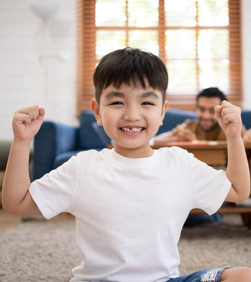 Happy child raises arms after effort is praised