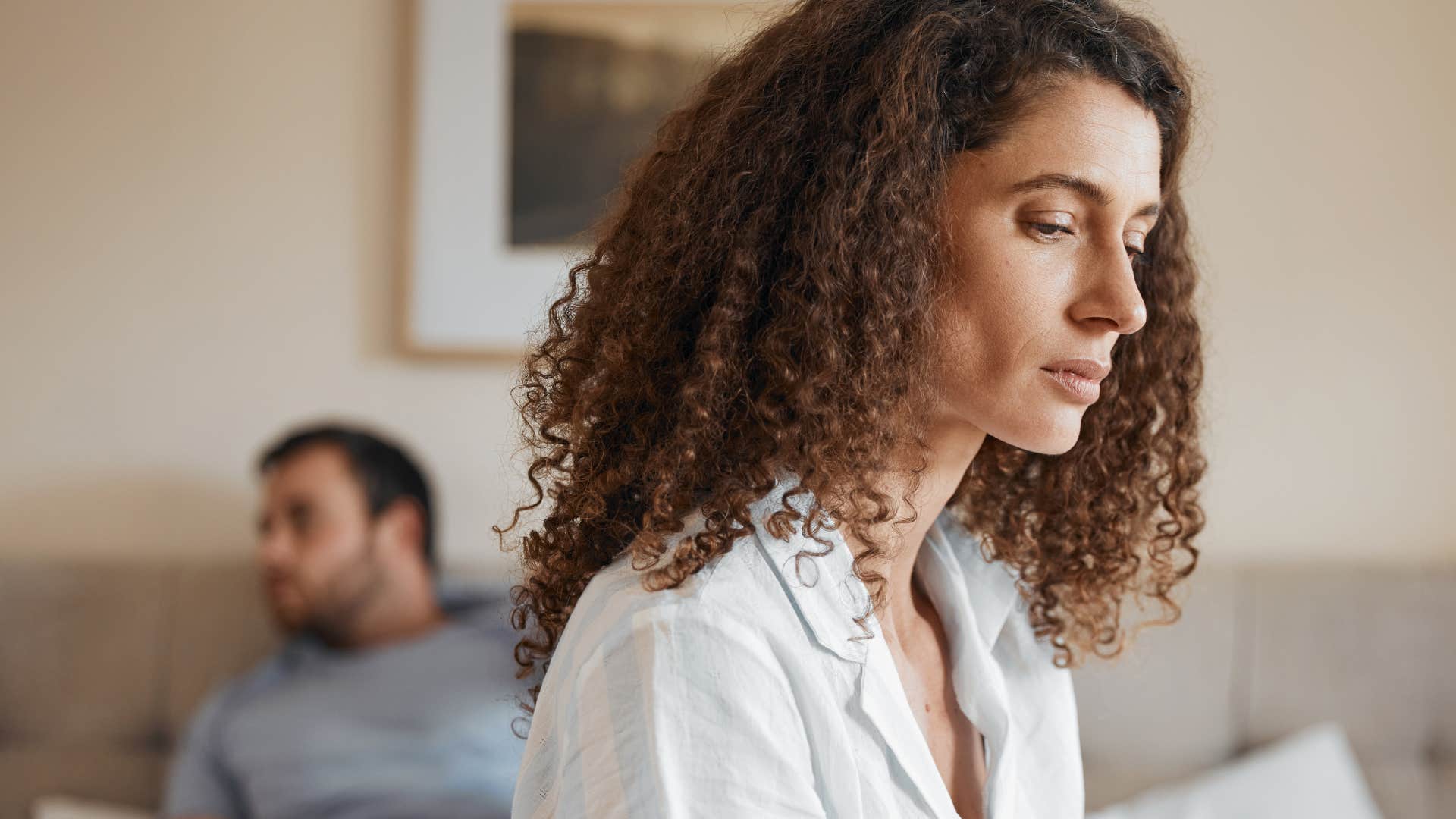 Sad woman looking away from her partner at home.