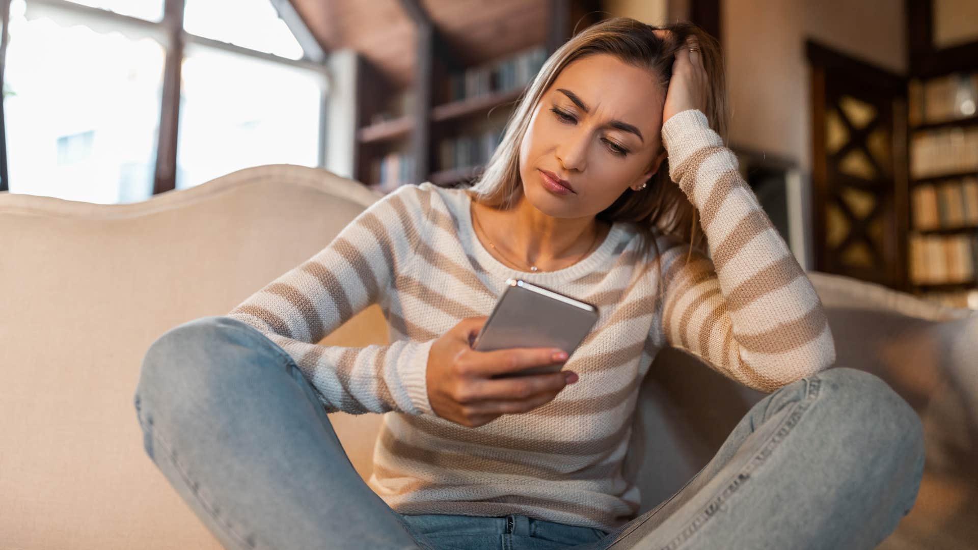 Woman looking upset staring at her phone. 