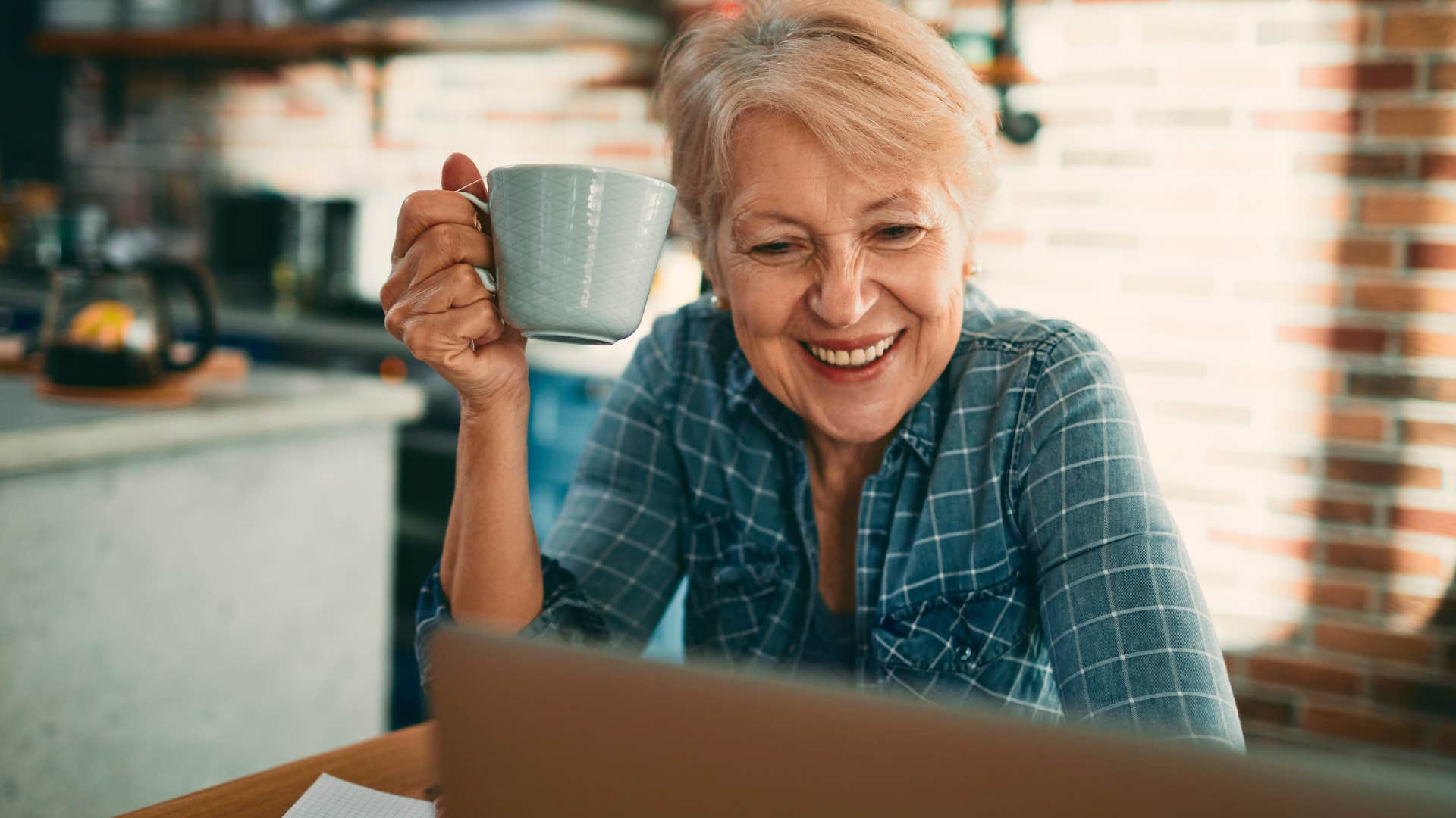 Woman smiling and holding up her coffee cup.