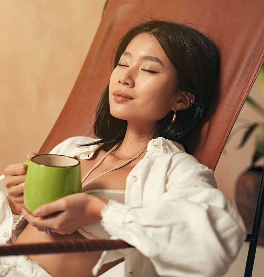 Woman with cup closes eyes to go neutral and relax