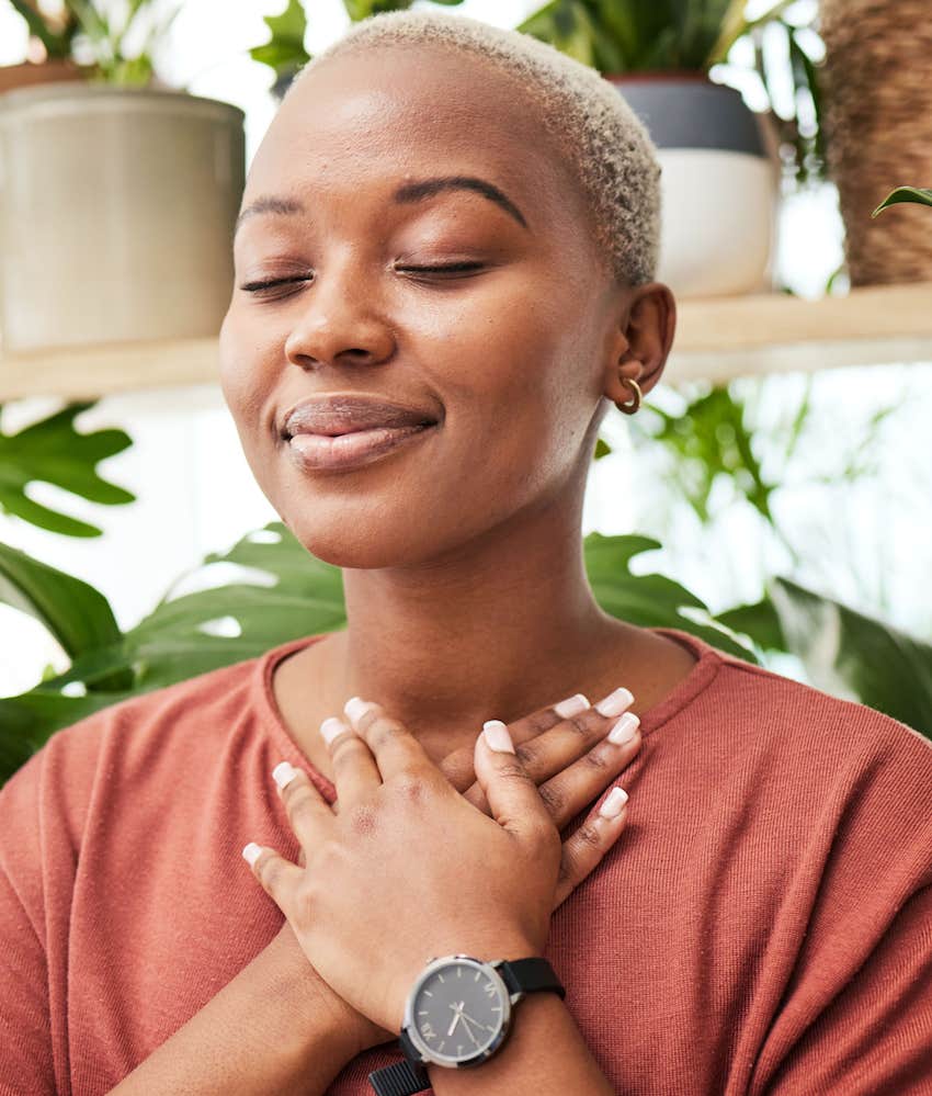 Woman with closed eyes and hands on chest gives herself permission to unwind