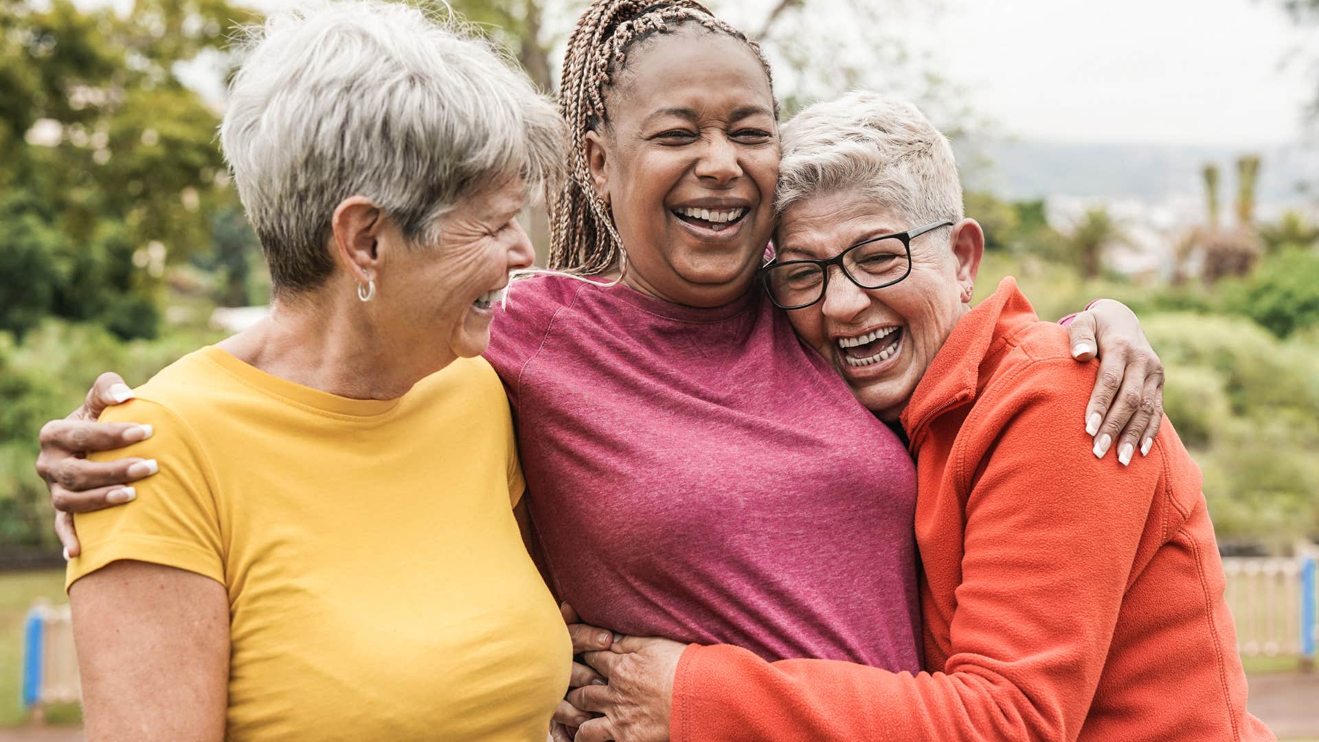 Three older women smiling and laughing together.