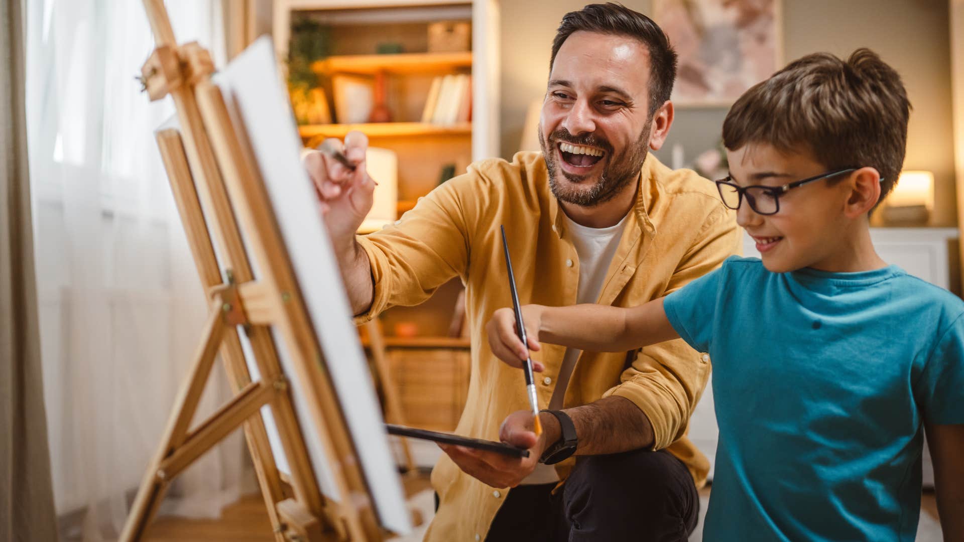 Dad painting on a canvas with his young son.