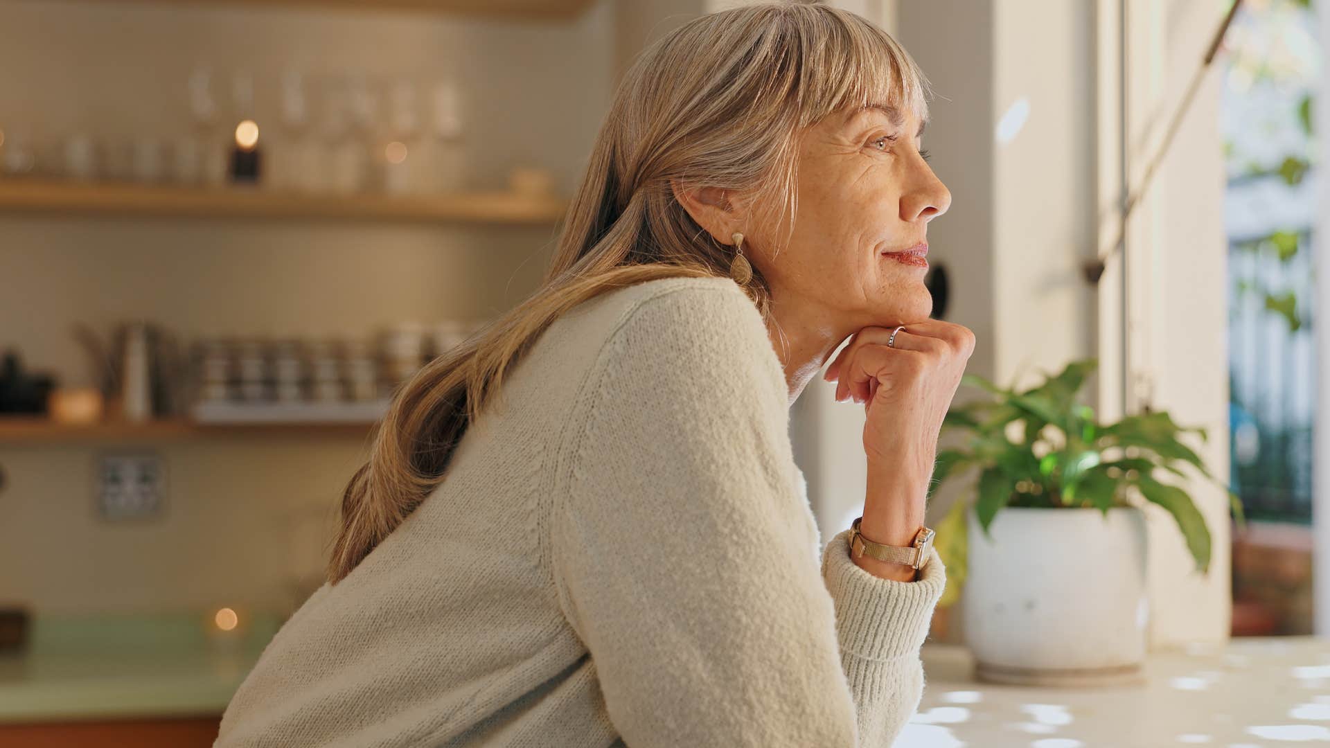 Older woman smiling and looking out the window.