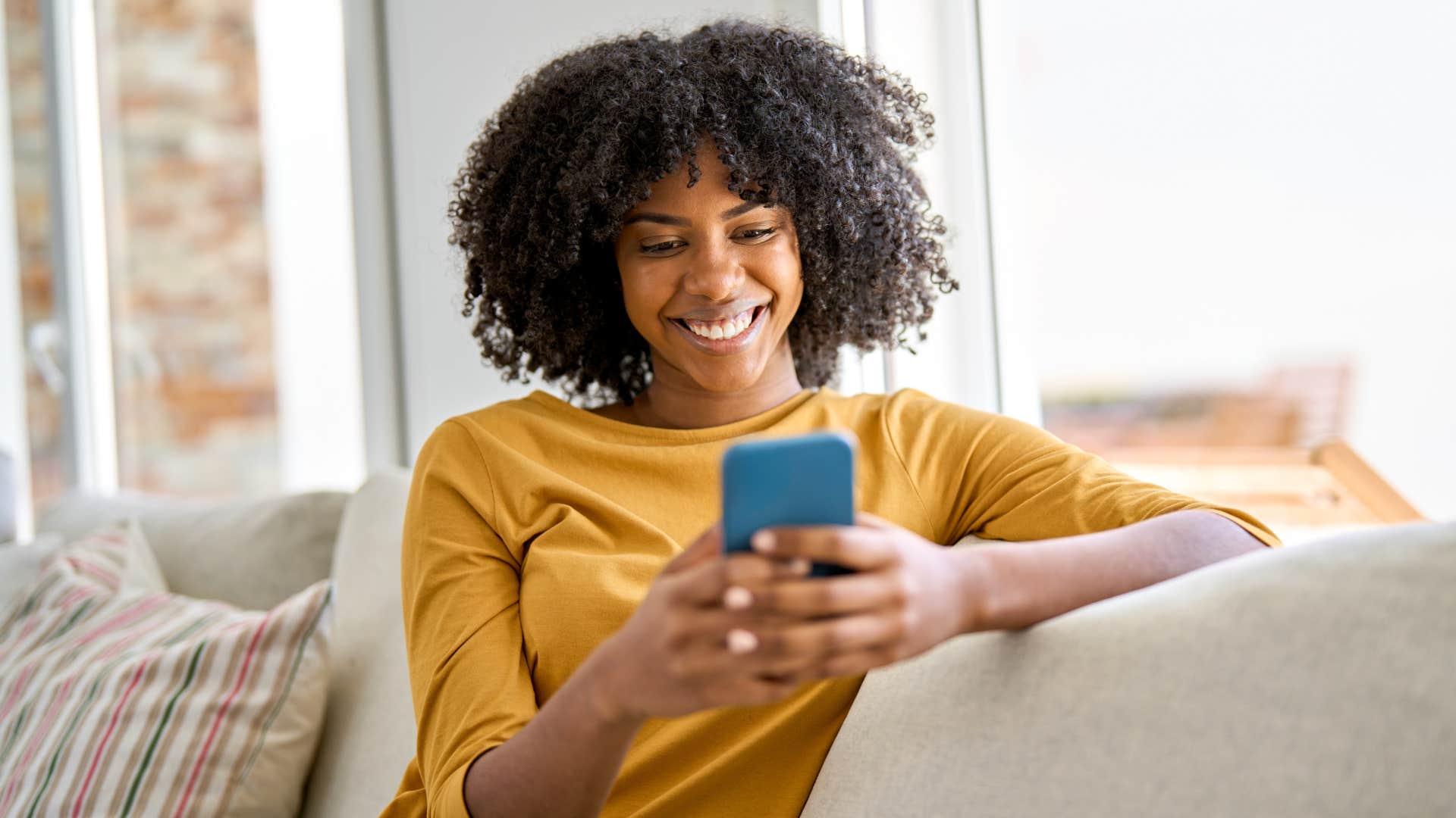 Woman smiling and looking at her cell phone.