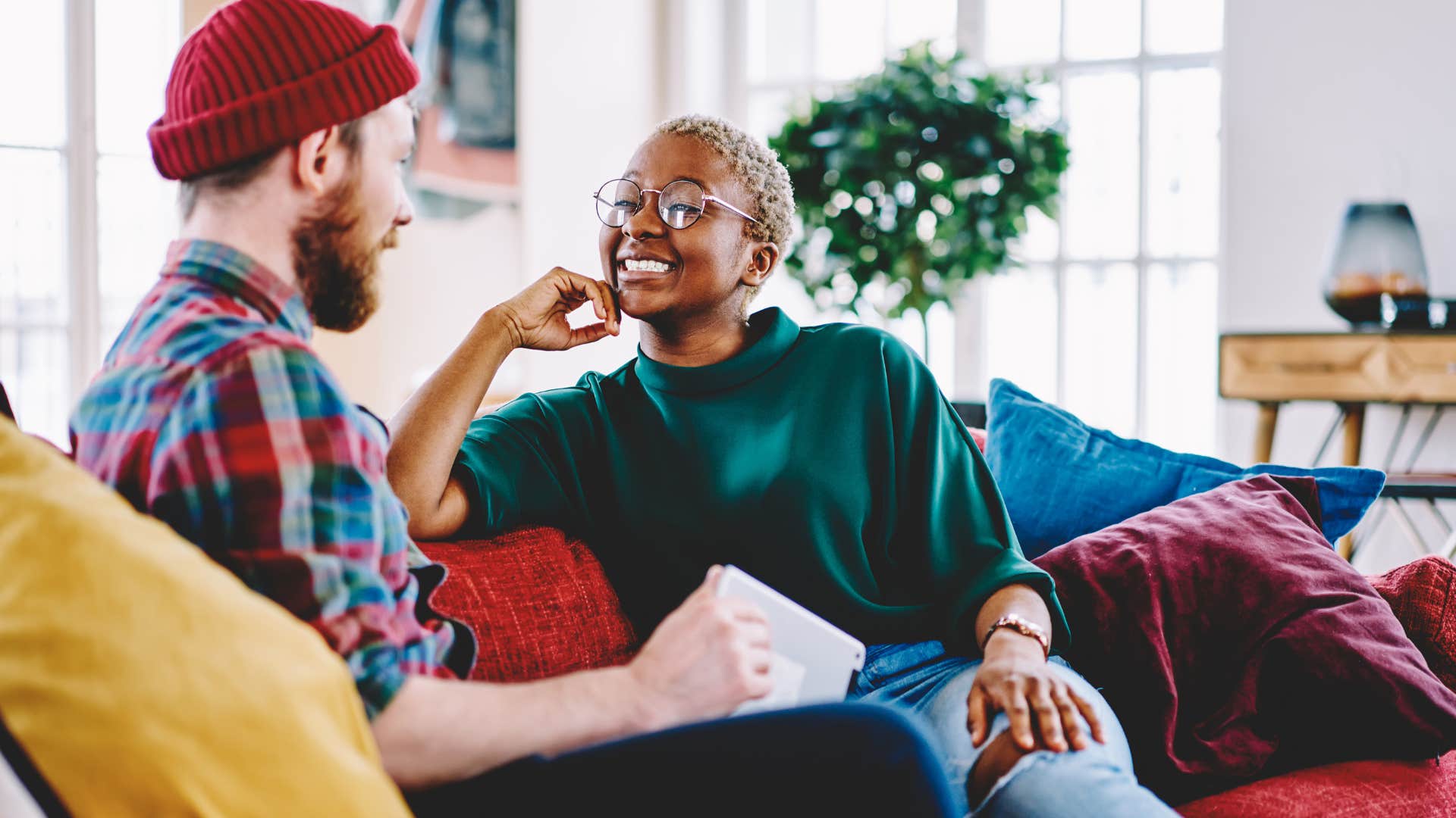 Man and woman smiling and talking together on a couch.