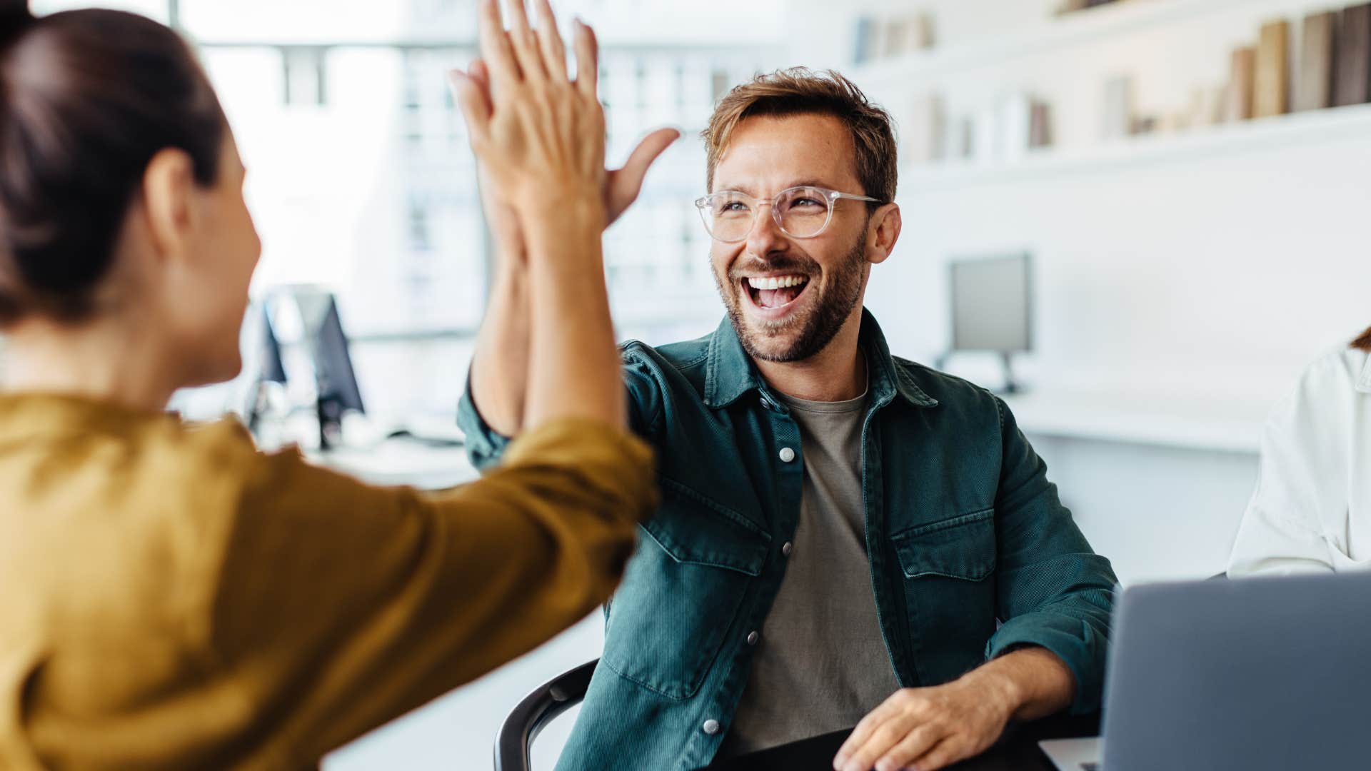 Smiling man giving a high five to a woman.