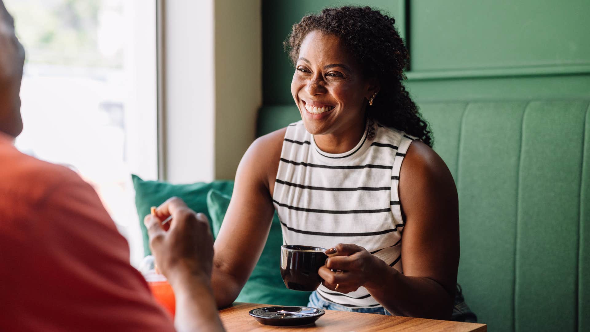 Woman smiling while sitting with a man at a coffee shop.