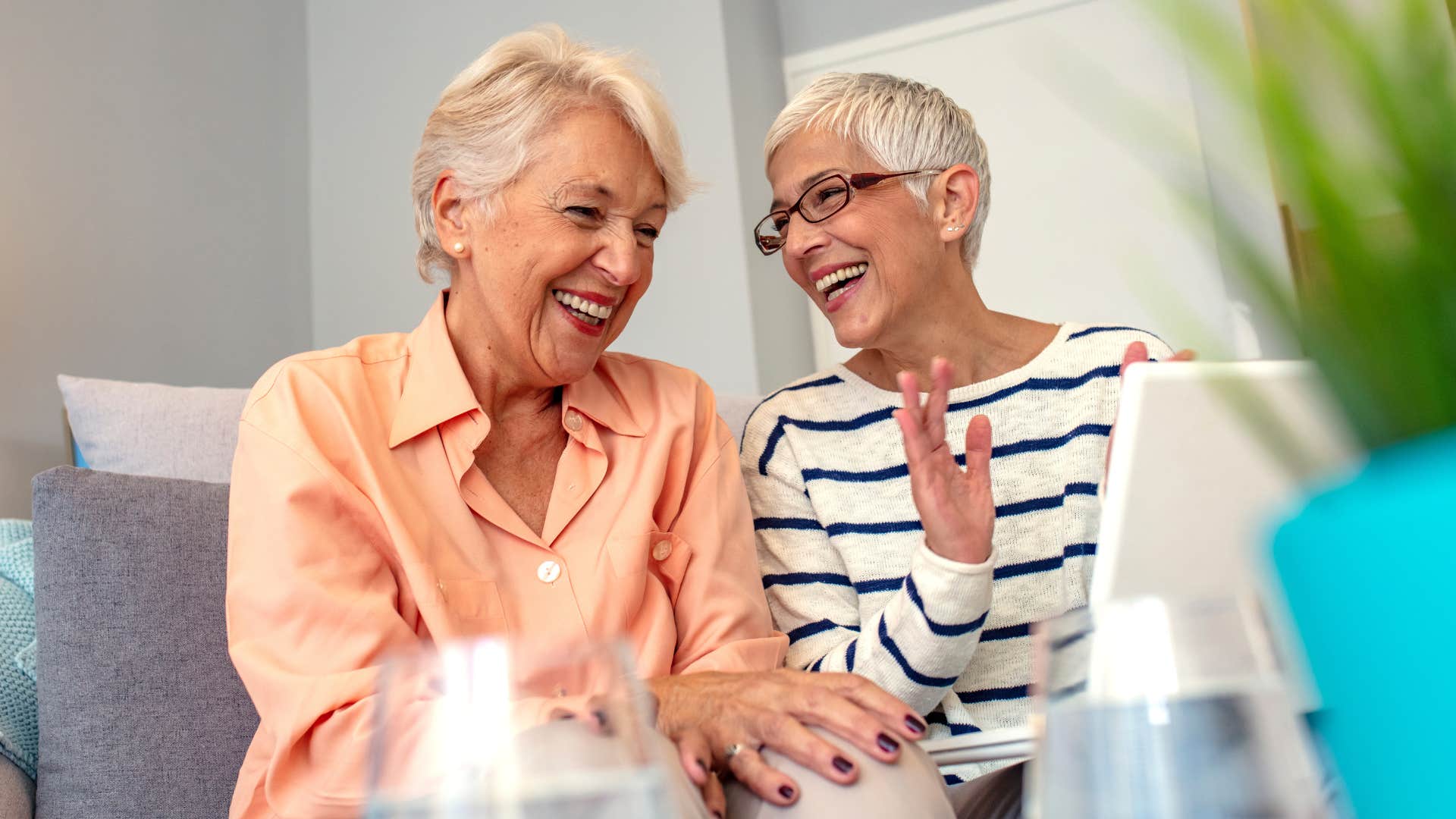 Two older women smiling and sitting together.