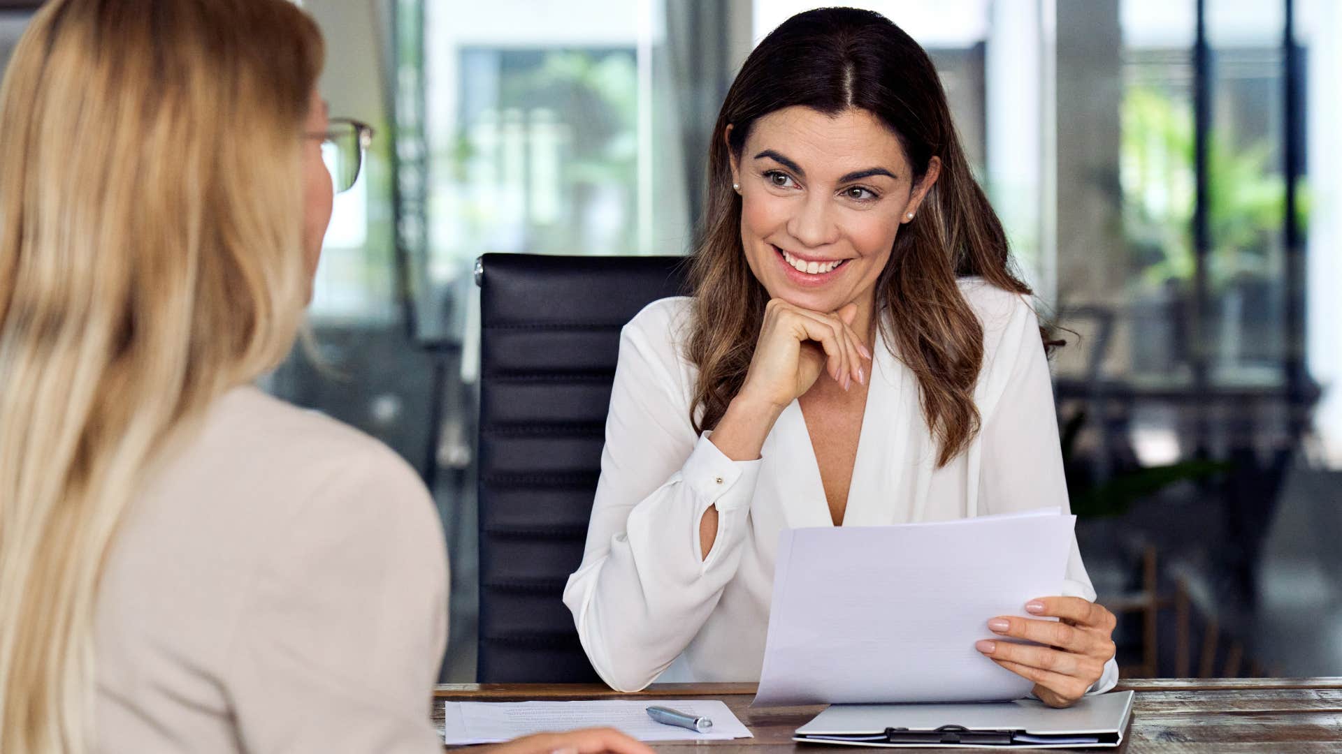 Woman smiling at work and talking to a peer.