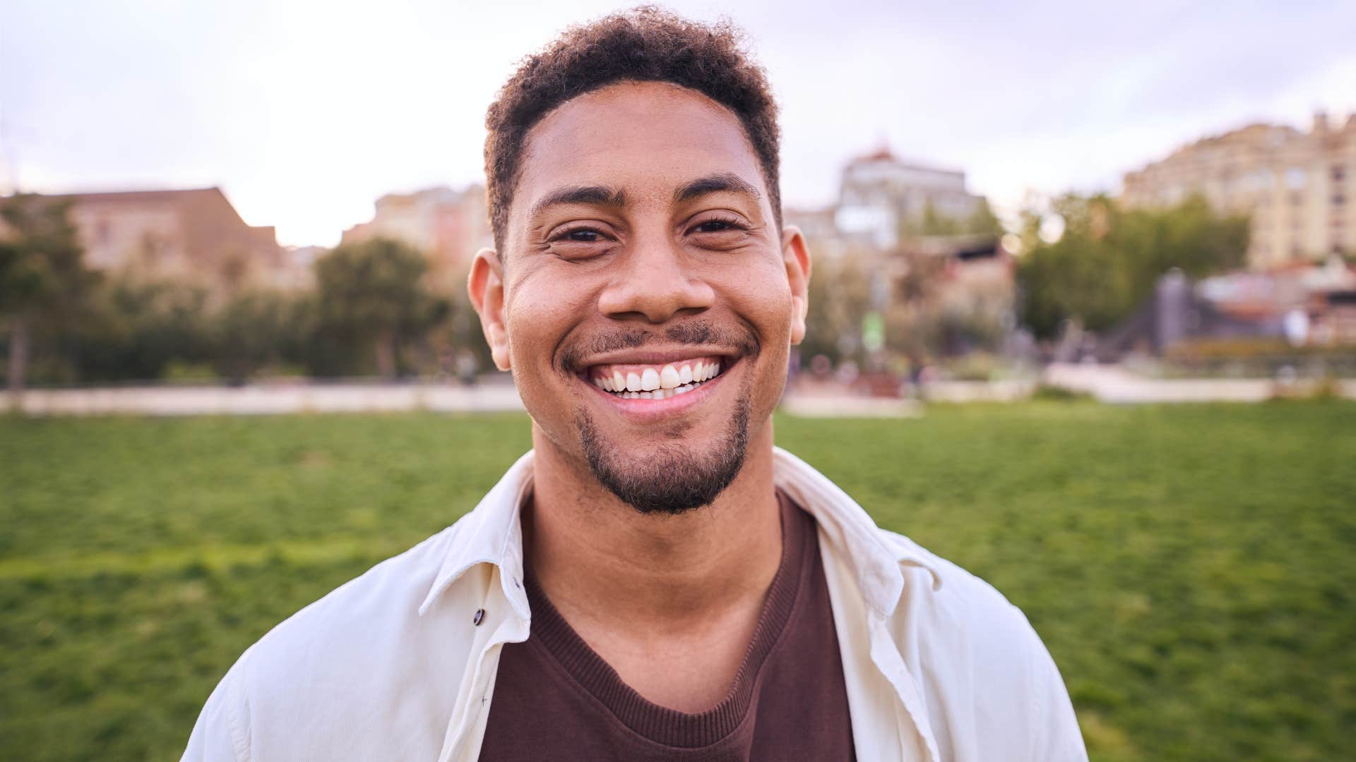 Man smiling while standing outside.