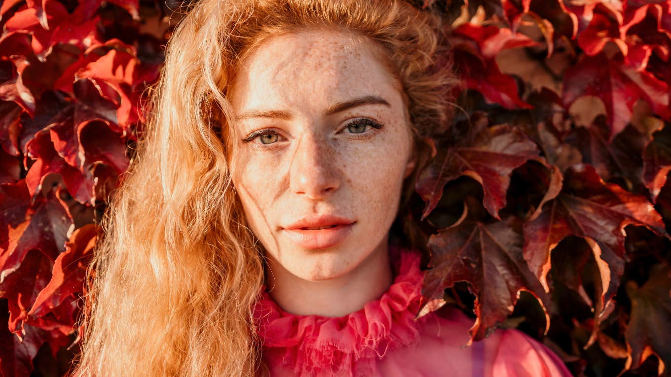 Close up shot of woman with curly blond hair and freckles looking at camera