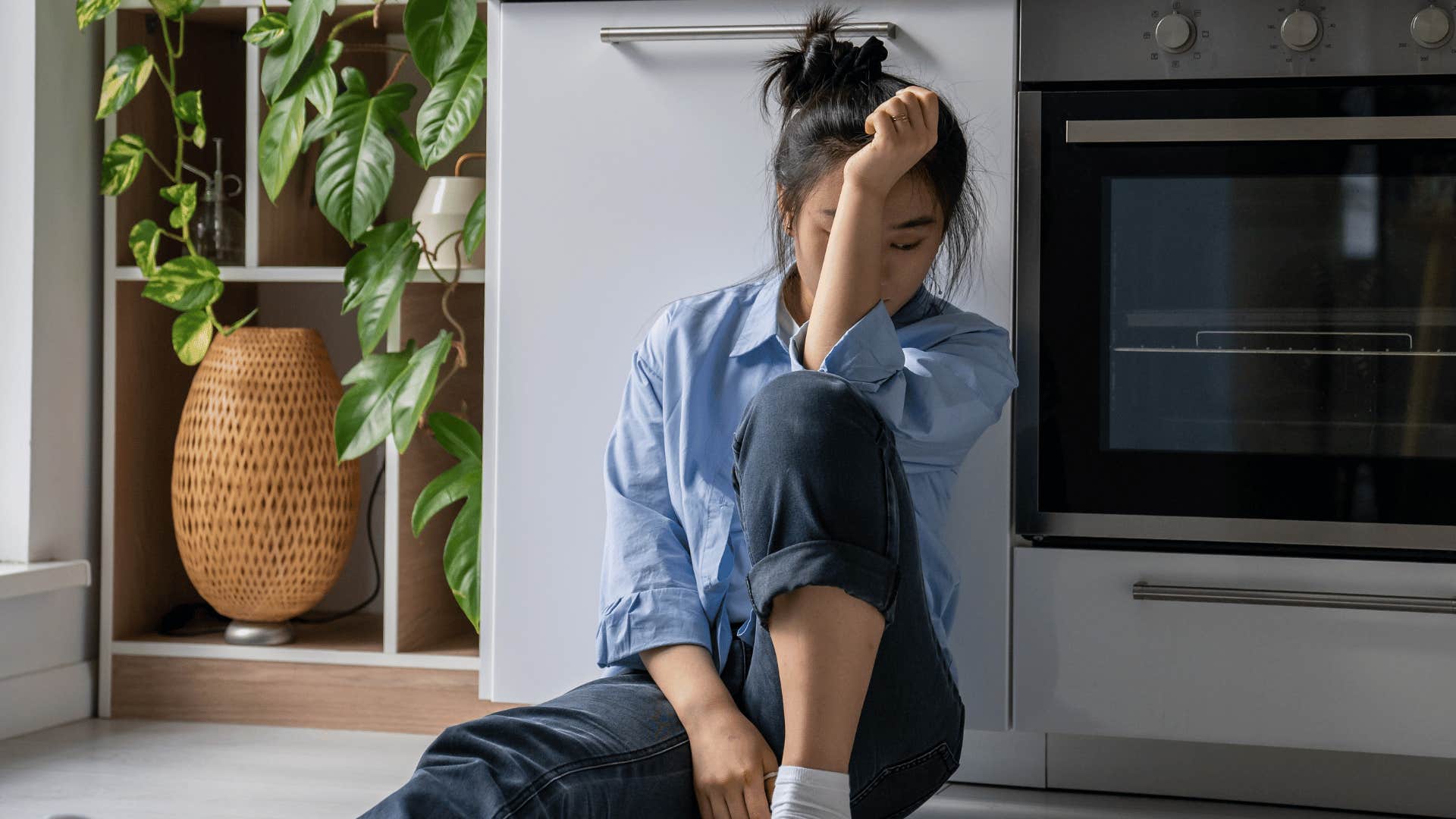 stressed out woman sitting on kitchen floor