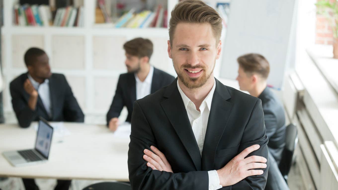 boss standing in front of employees sitting at desk