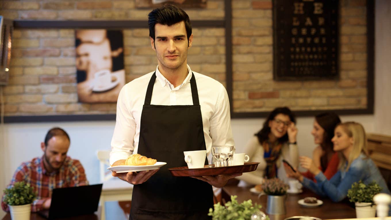 Waiter looking serious while carrying trays of food