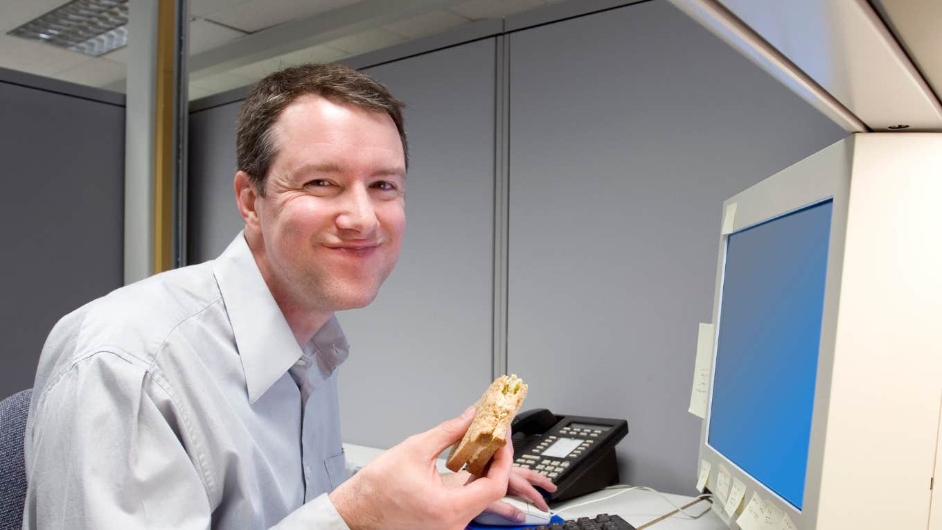 man eating sandwich while working