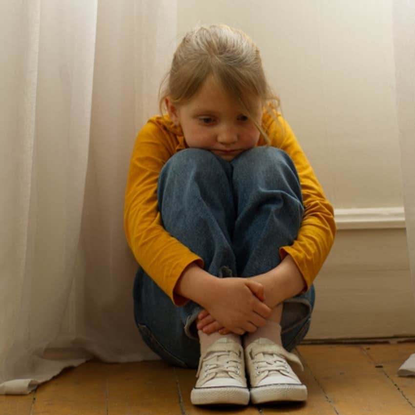 sad little girl sitting on floor 