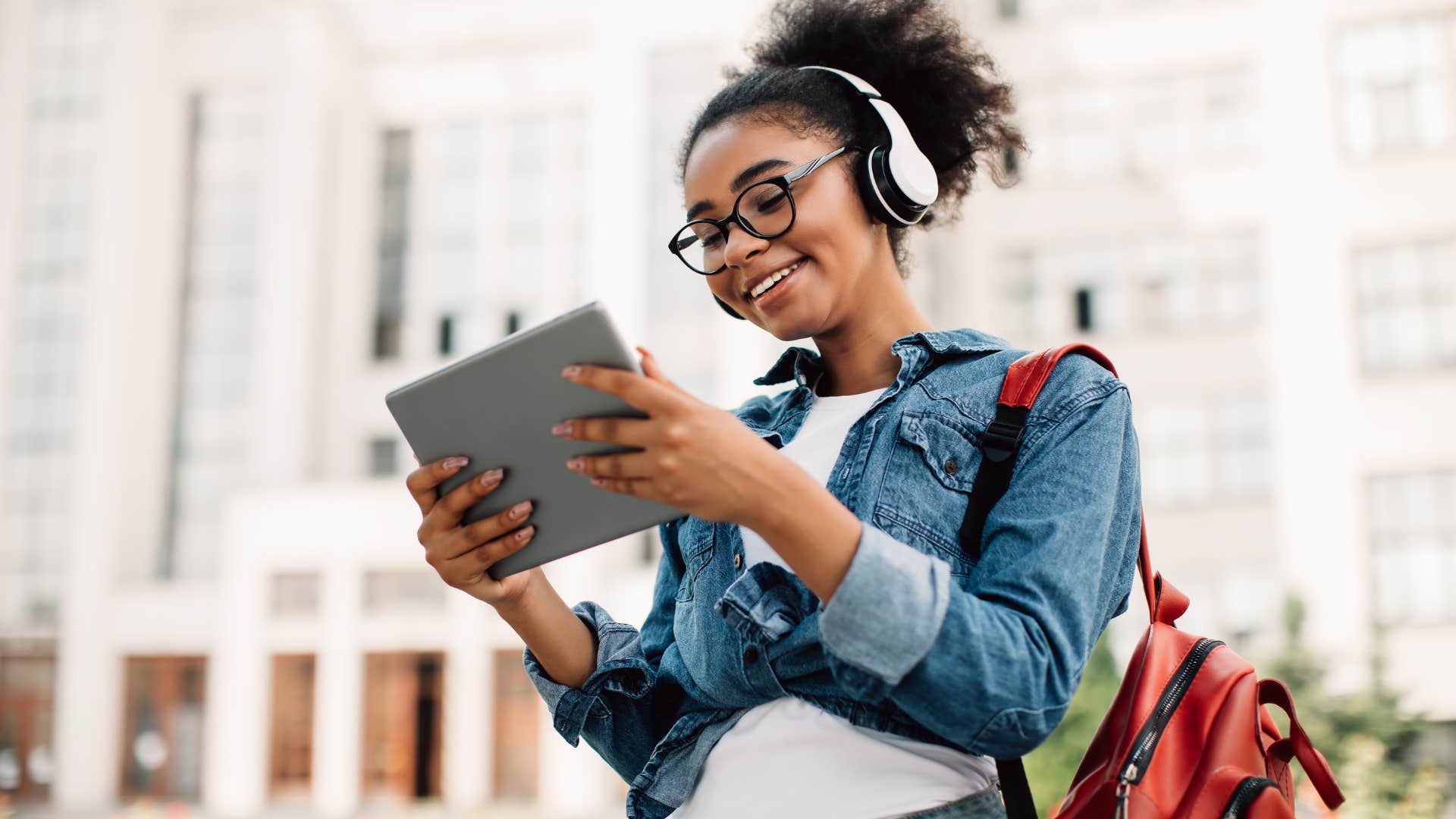 Teenage girl smiling at school holding her tablet.