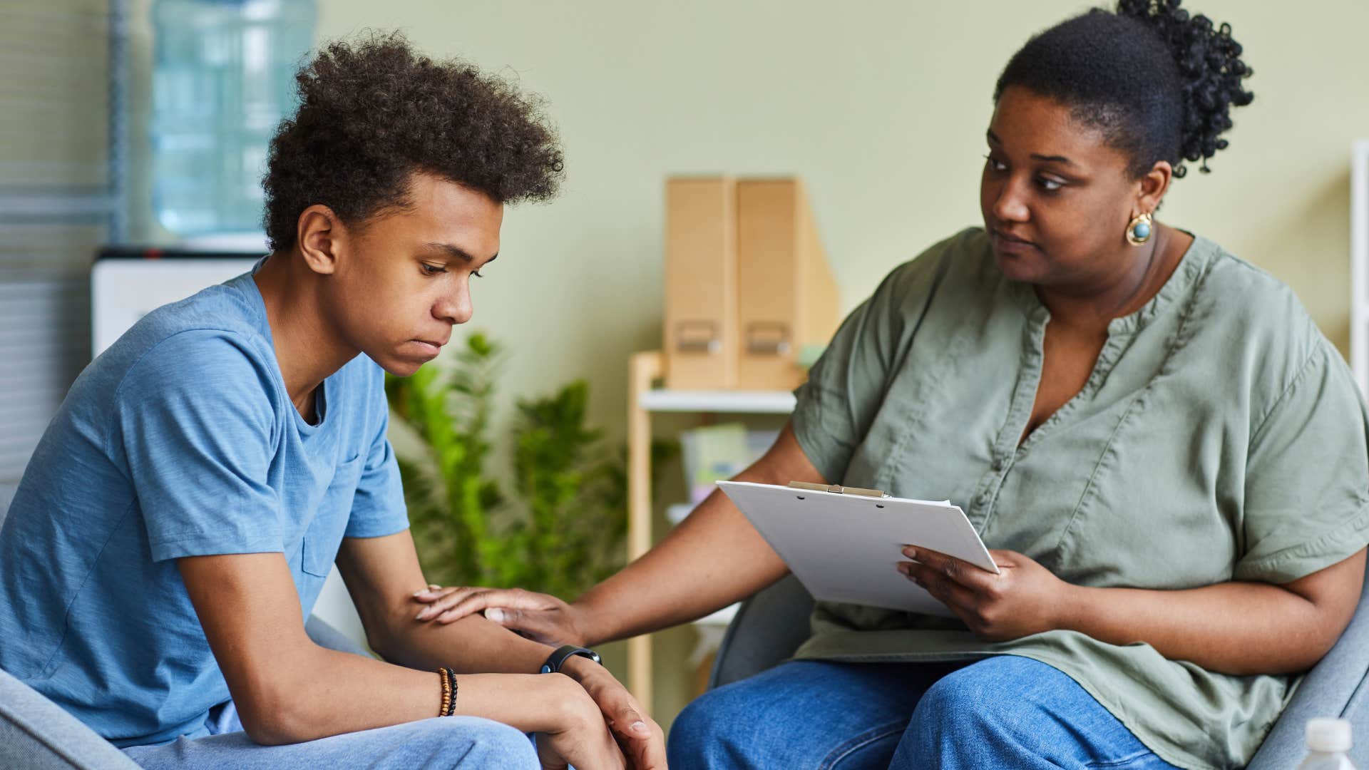 Teenage boy looking sad next to an older woman.