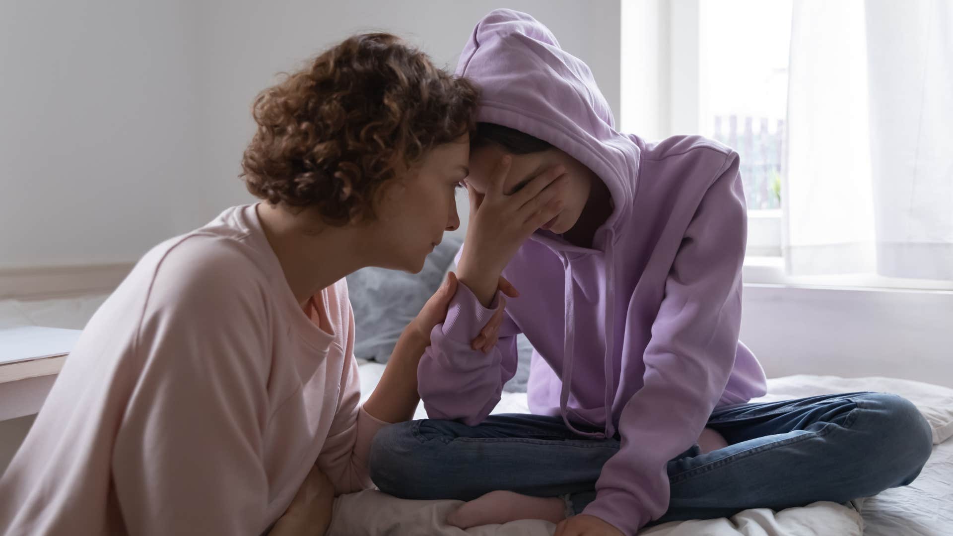 Teenager looking sad while sitting next to her mom.